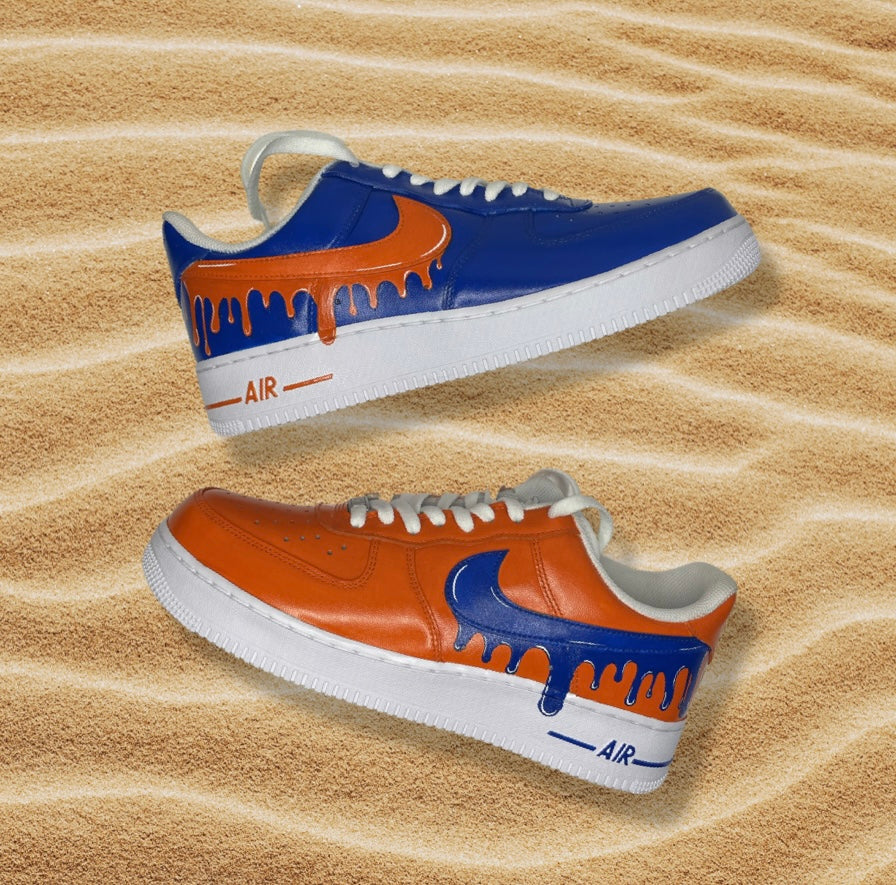 Custom streetwear sneakers with blue and orange drip designs on sand background