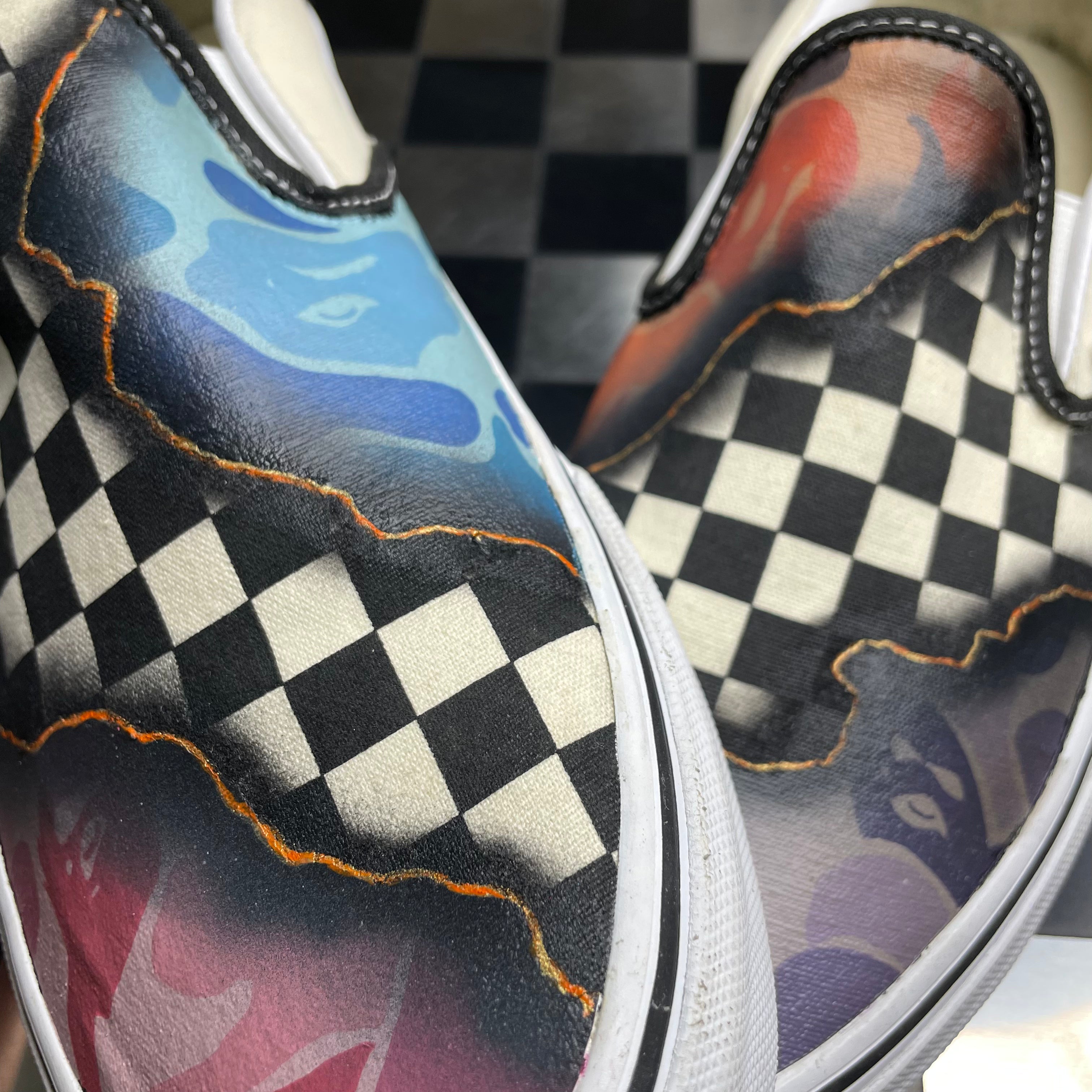 Close-up of checkerboard slip-on sneakers with colorful, abstract street art design