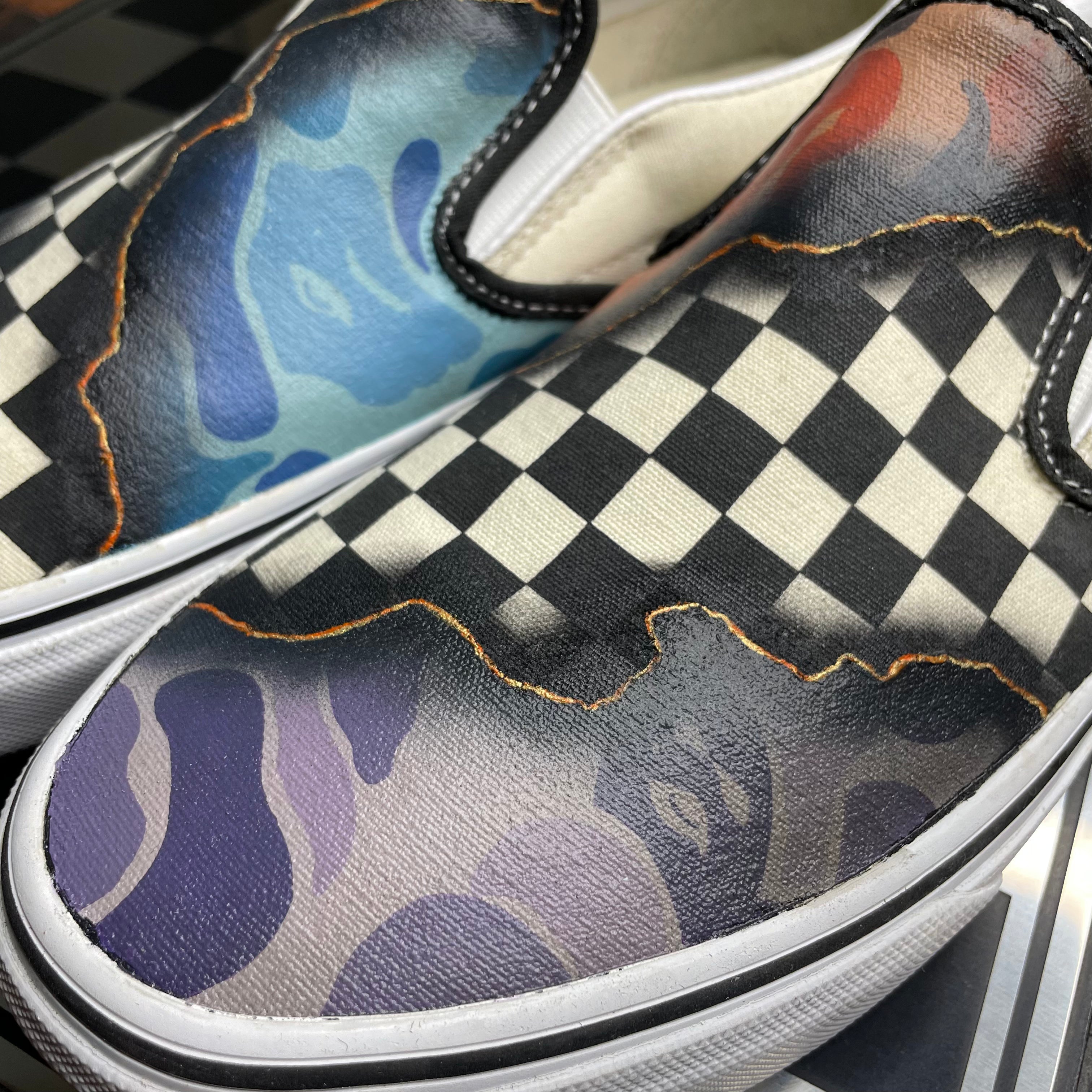 Slip-on sneakers with black and white checkerboard pattern and colorful camouflage accents