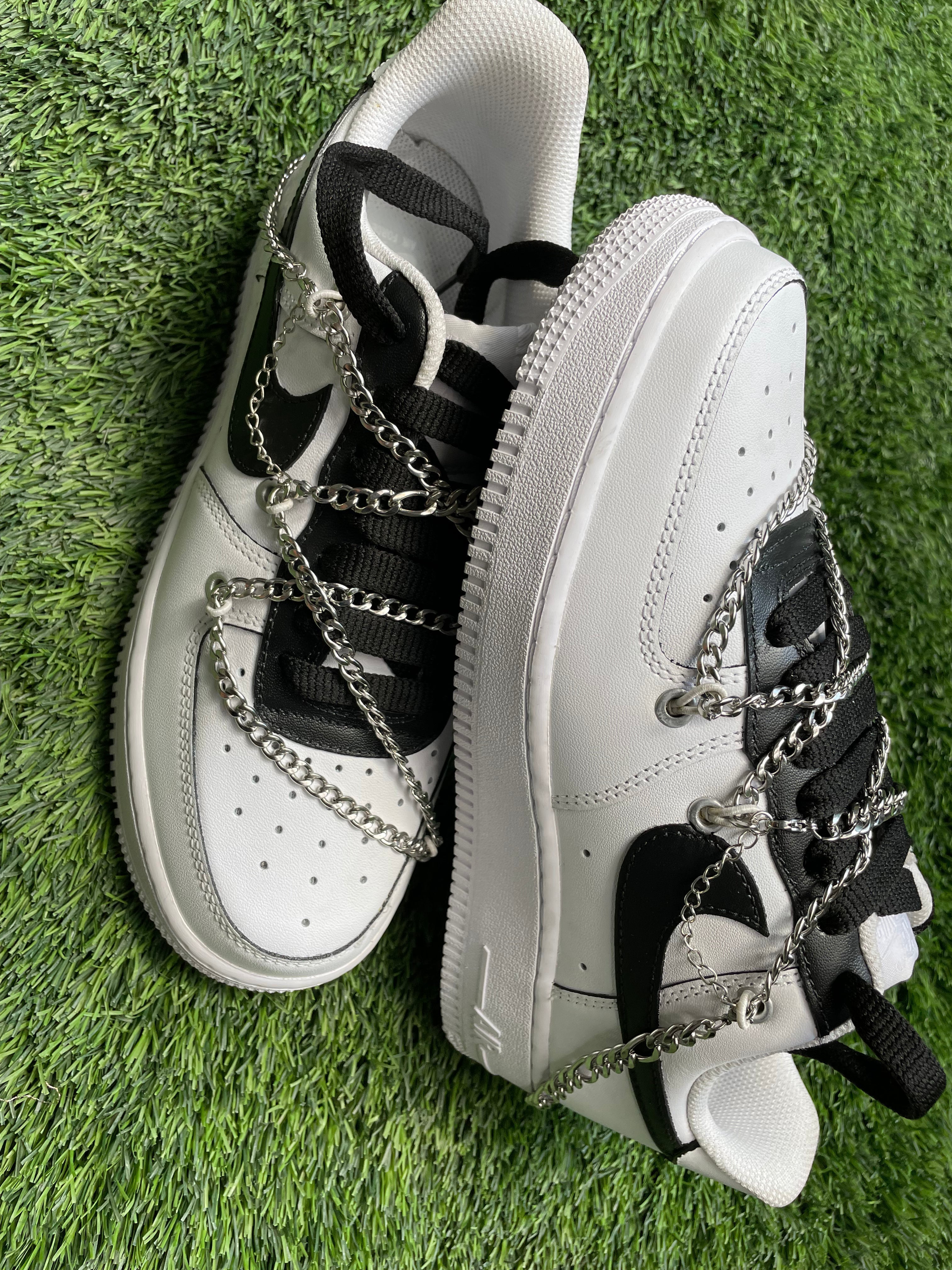 White and black streetwear sneakers with silver chain details on green grass