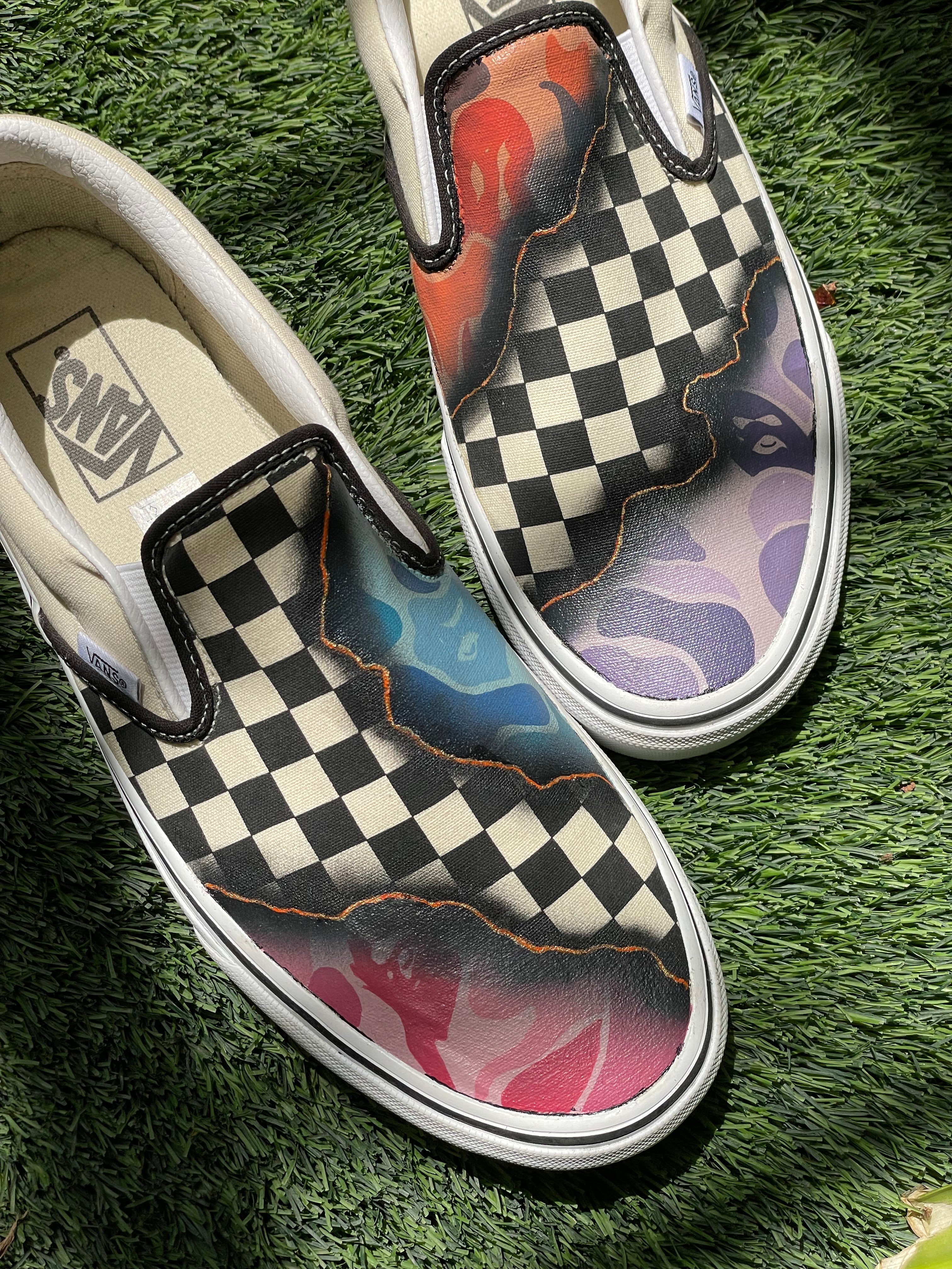 Checkerboard slip-on sneakers with multicolor flame design on grass