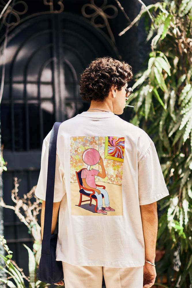 Man wearing graphic streetwear t-shirt with colorful cartoon design on back, outdoors