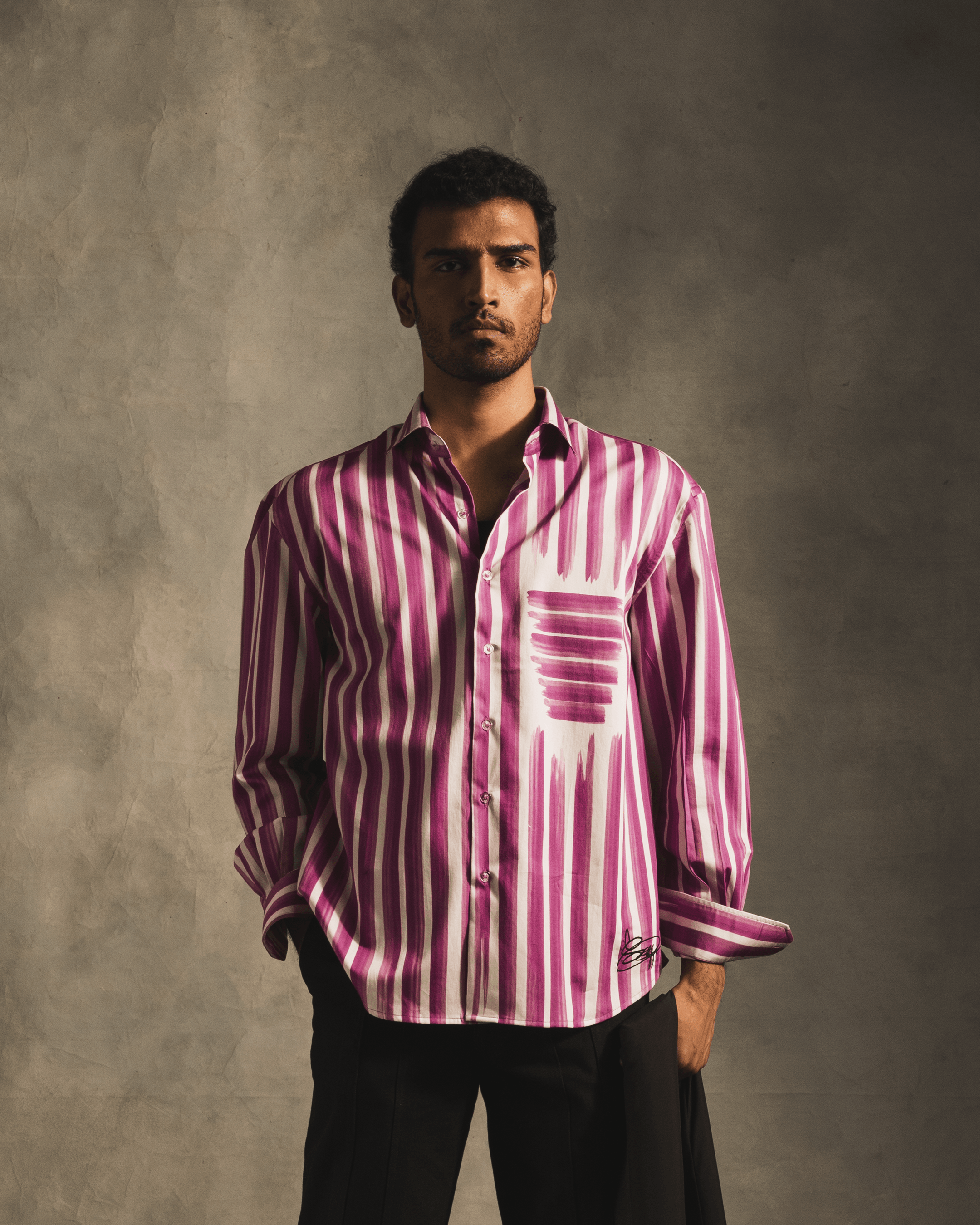Man wearing a pink and white striped button-up shirt, streetwear fashion, studio backdrop