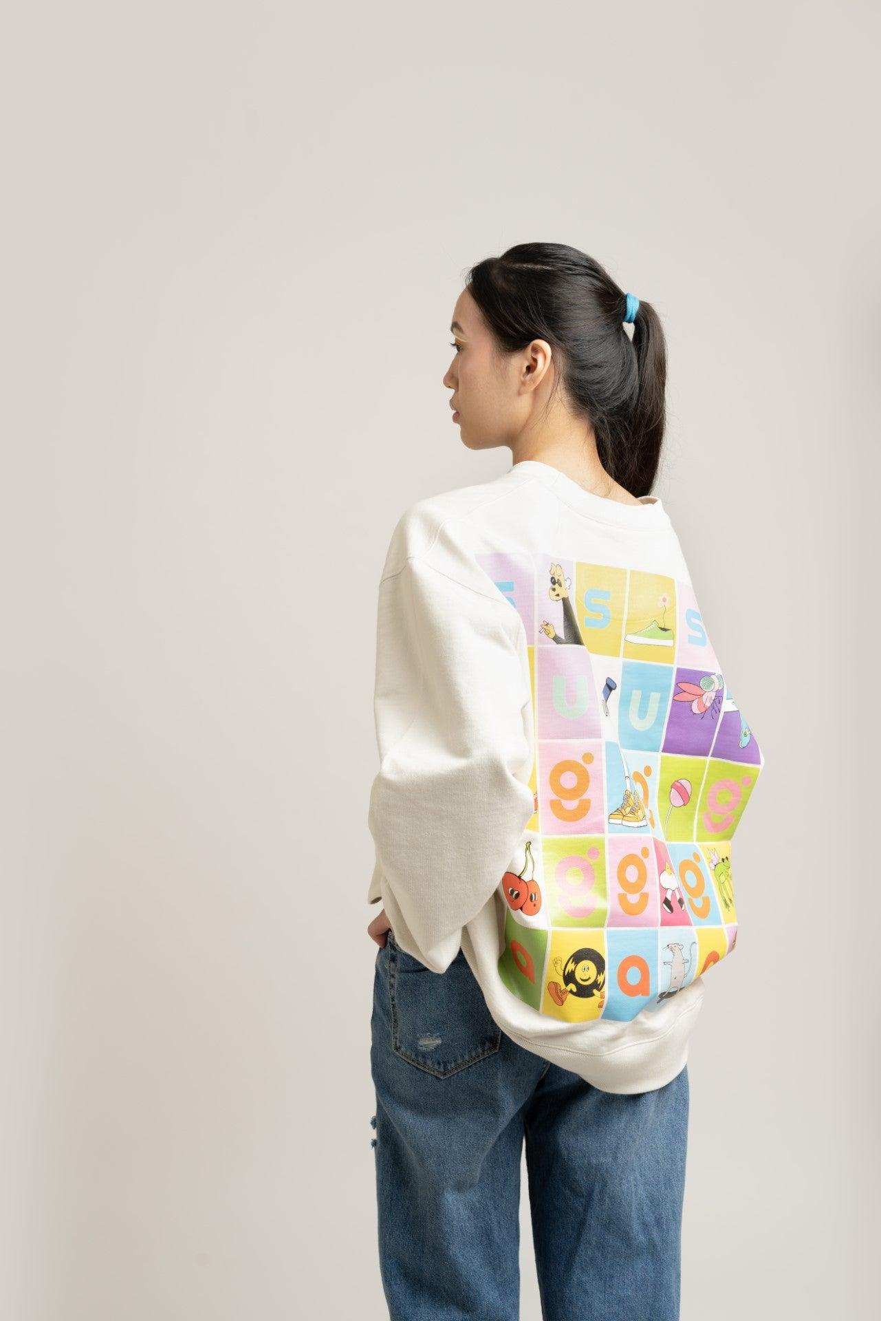 Woman wearing a graphic streetwear sweatshirt with colorful cartoon squares on the back