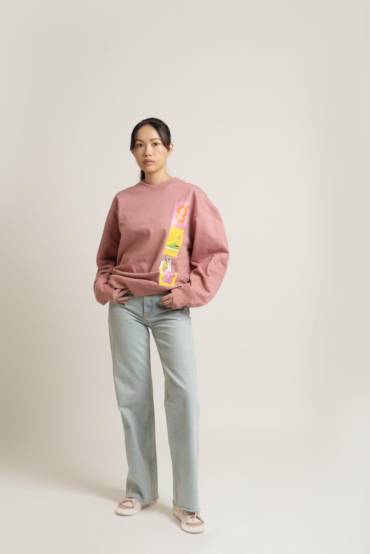 Woman in pink graphic sweatshirt, light blue jeans, and sneakers, streetwear fashion