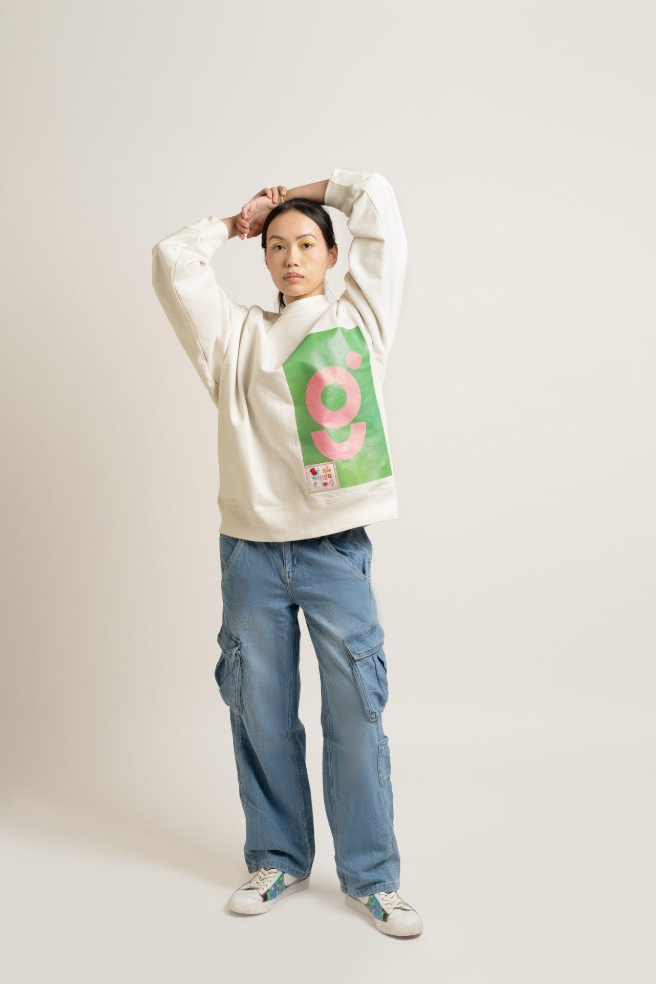 Model in streetwear style, wearing a cream graphic sweatshirt, blue cargo jeans, and sneakers