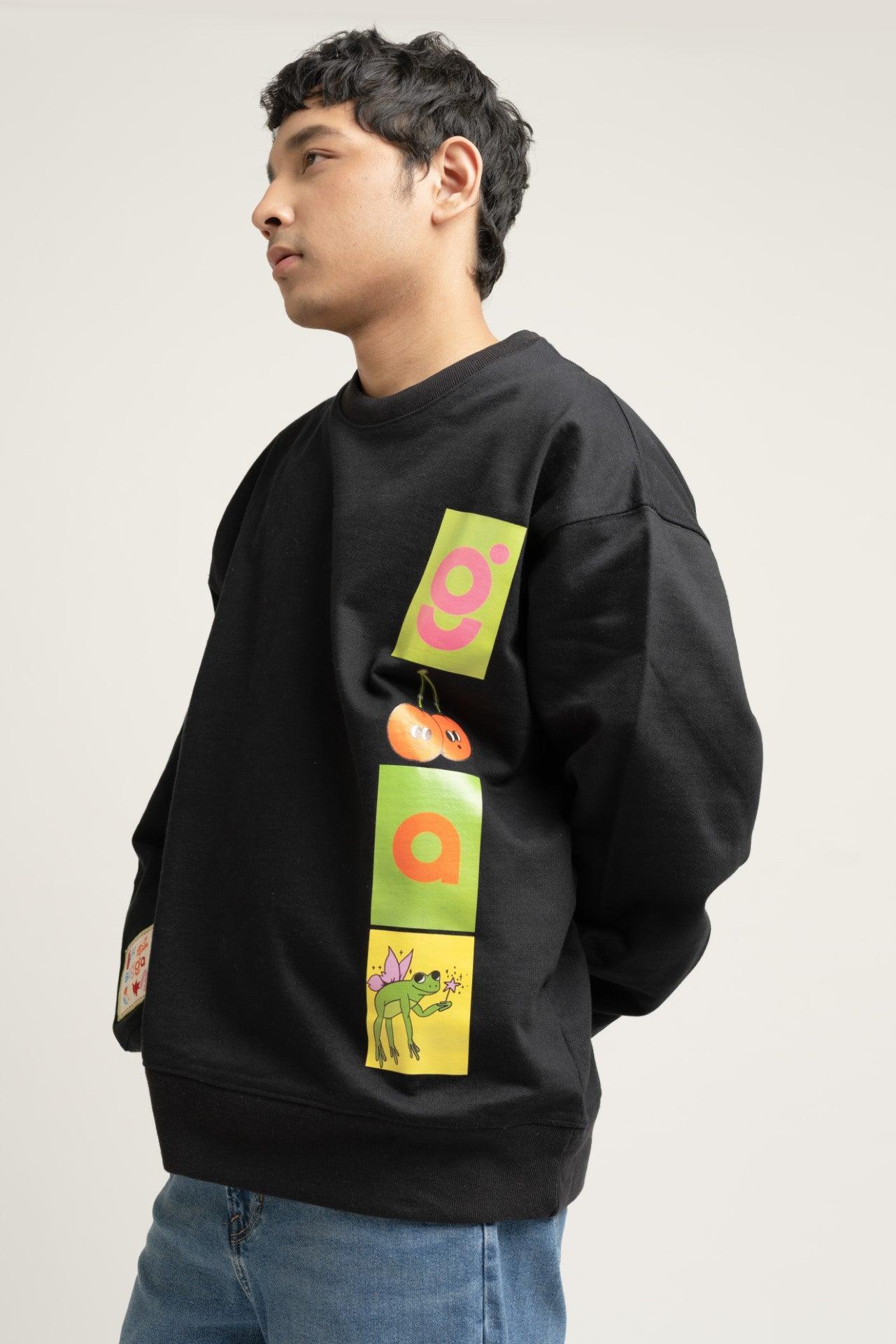 Man wearing black streetwear sweatshirt with colorful graphic patches and blue jeans