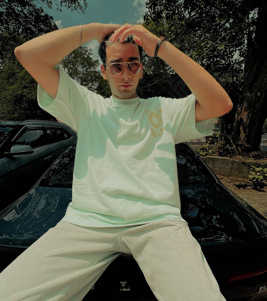 Man in white streetwear t-shirt and sunglasses posing outdoors on a black car