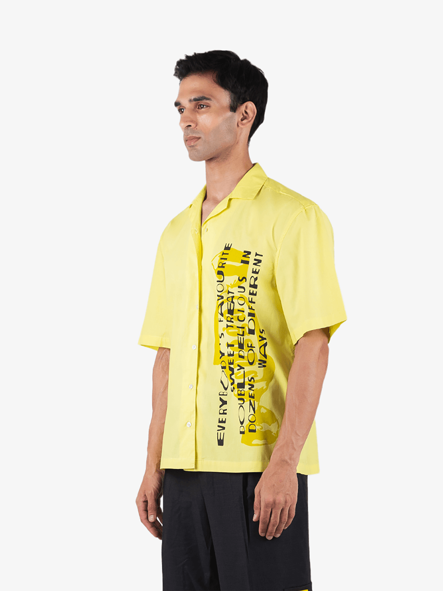 Man wearing a yellow short sleeve streetwear shirt with bold vertical text graphic