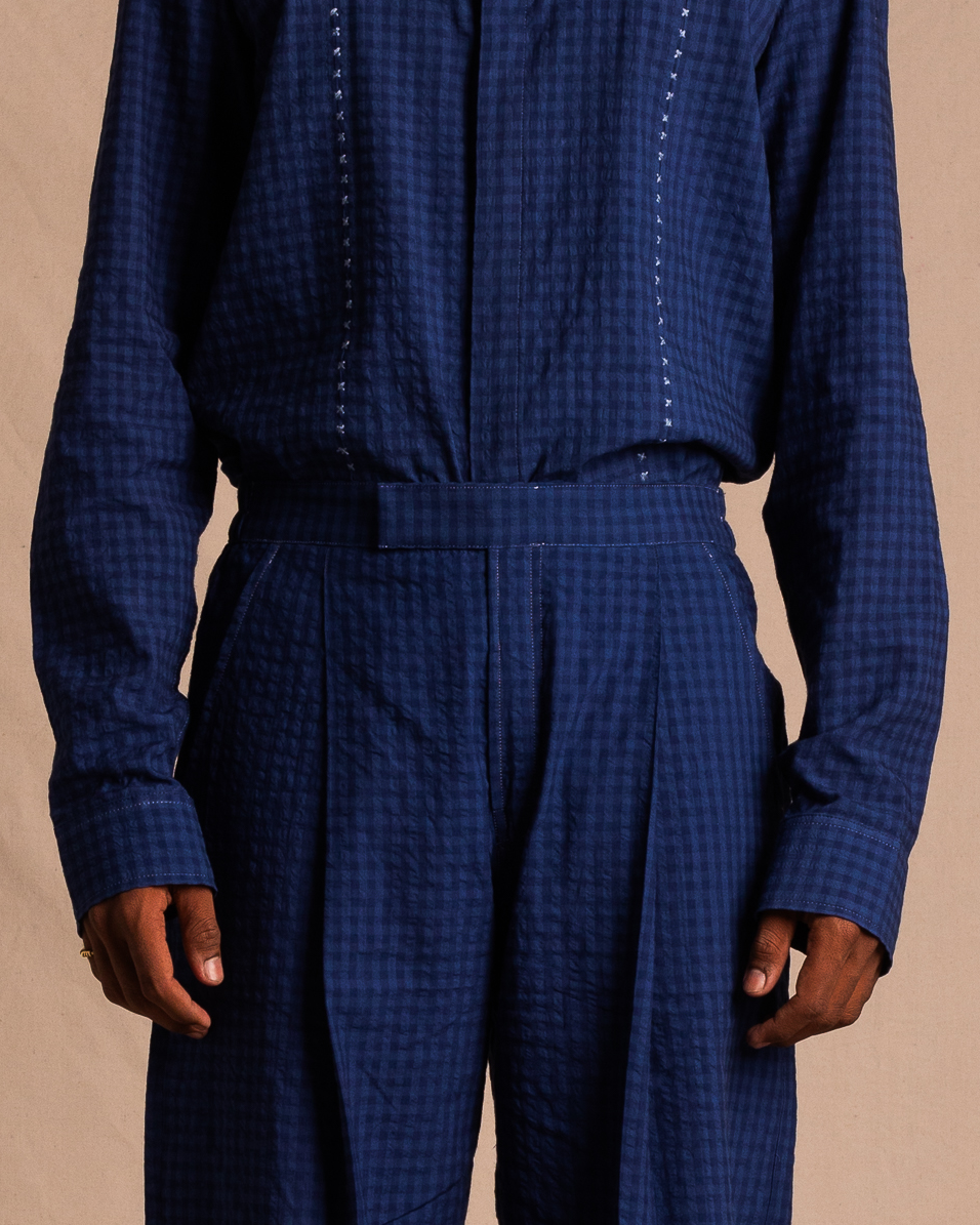 Model wearing blue checkered streetwear shirt and matching pants, neutral background