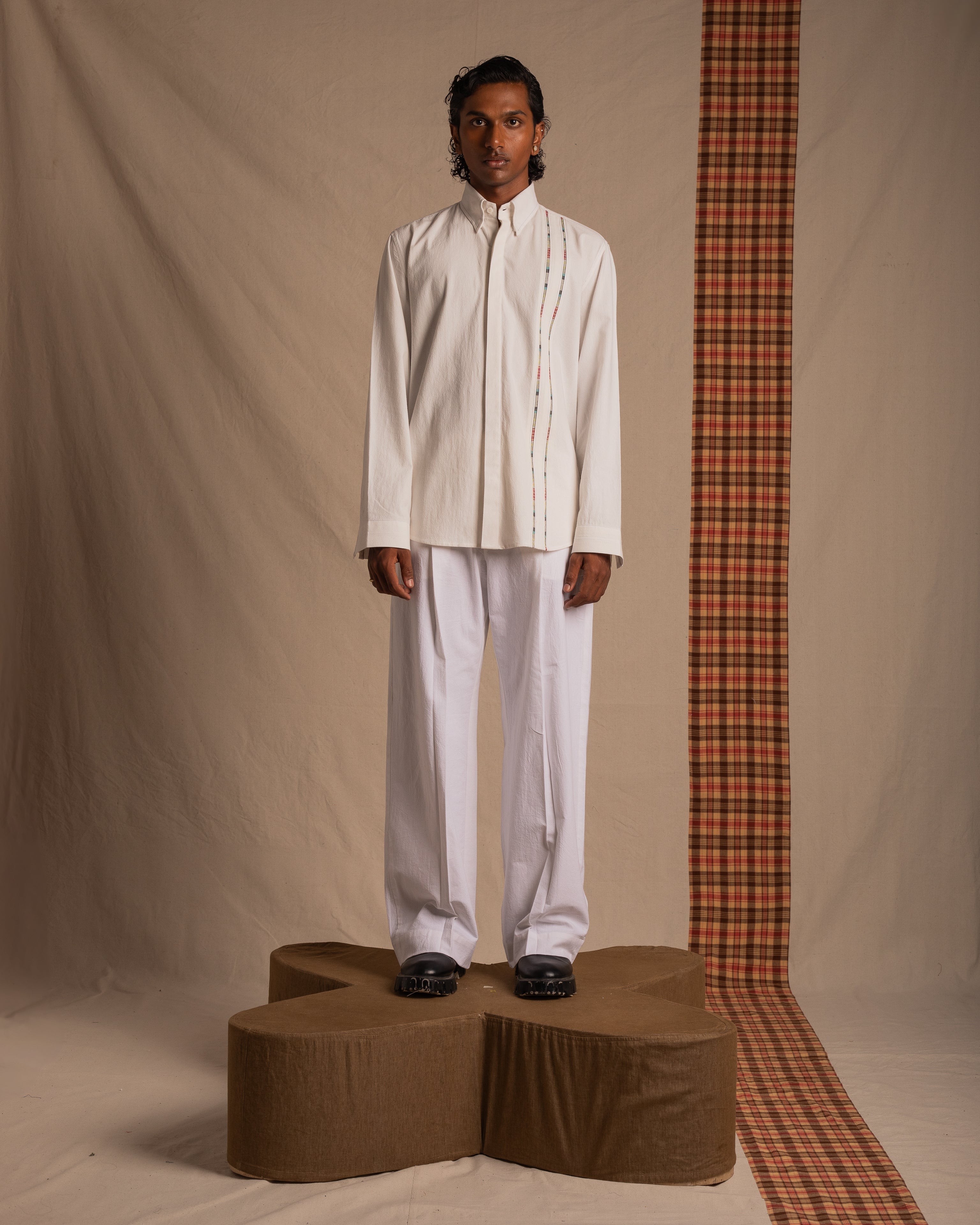 Man modeling modern white shirt and trousers with subtle stripe detail, streetwear fashion