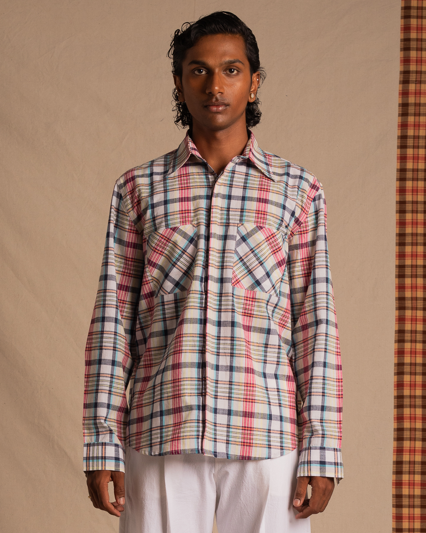 Man wearing a colorful plaid long sleeve shirt and white pants, streetwear fashion style