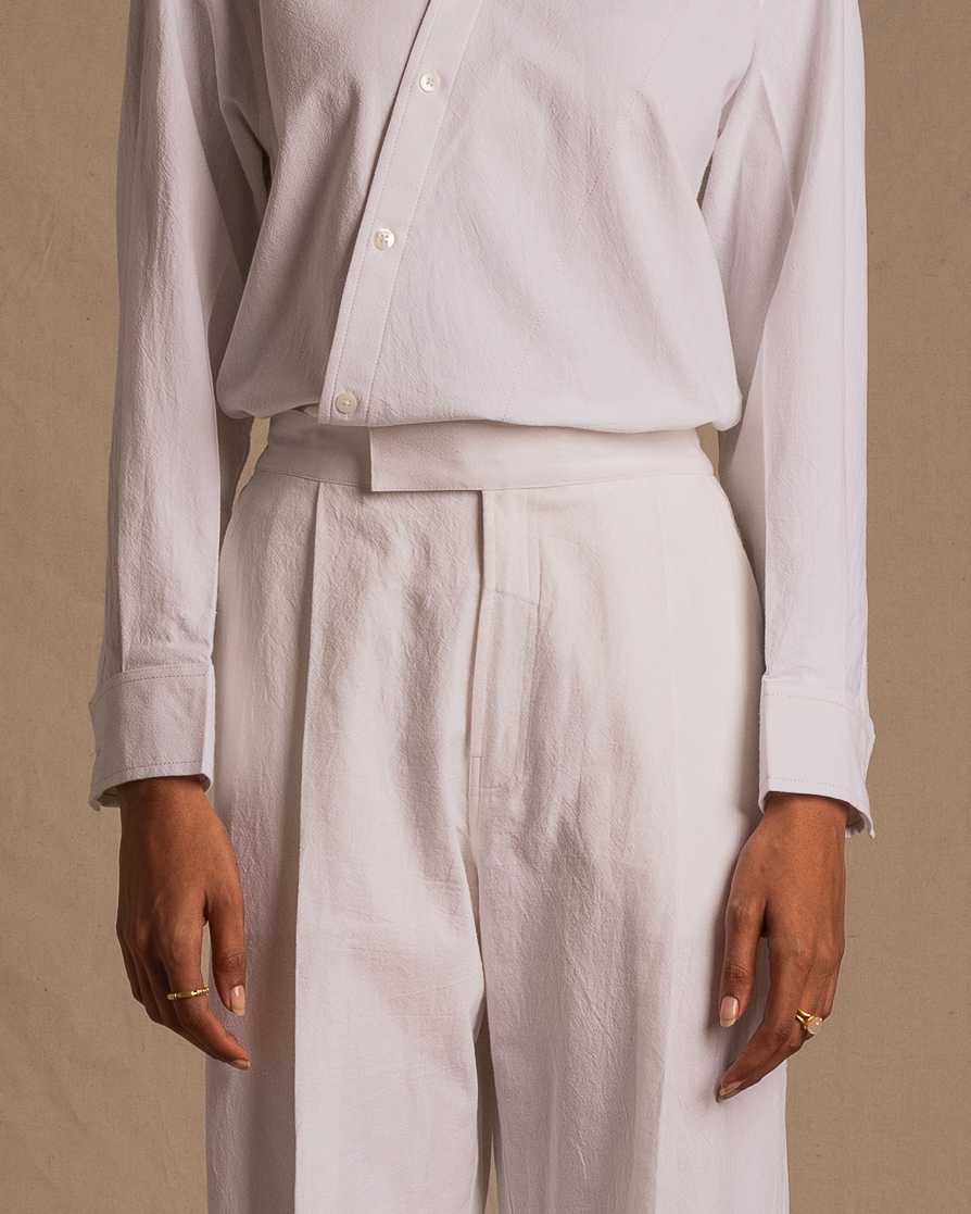Person wearing white button-up shirt and white high-waisted pants with gold rings
