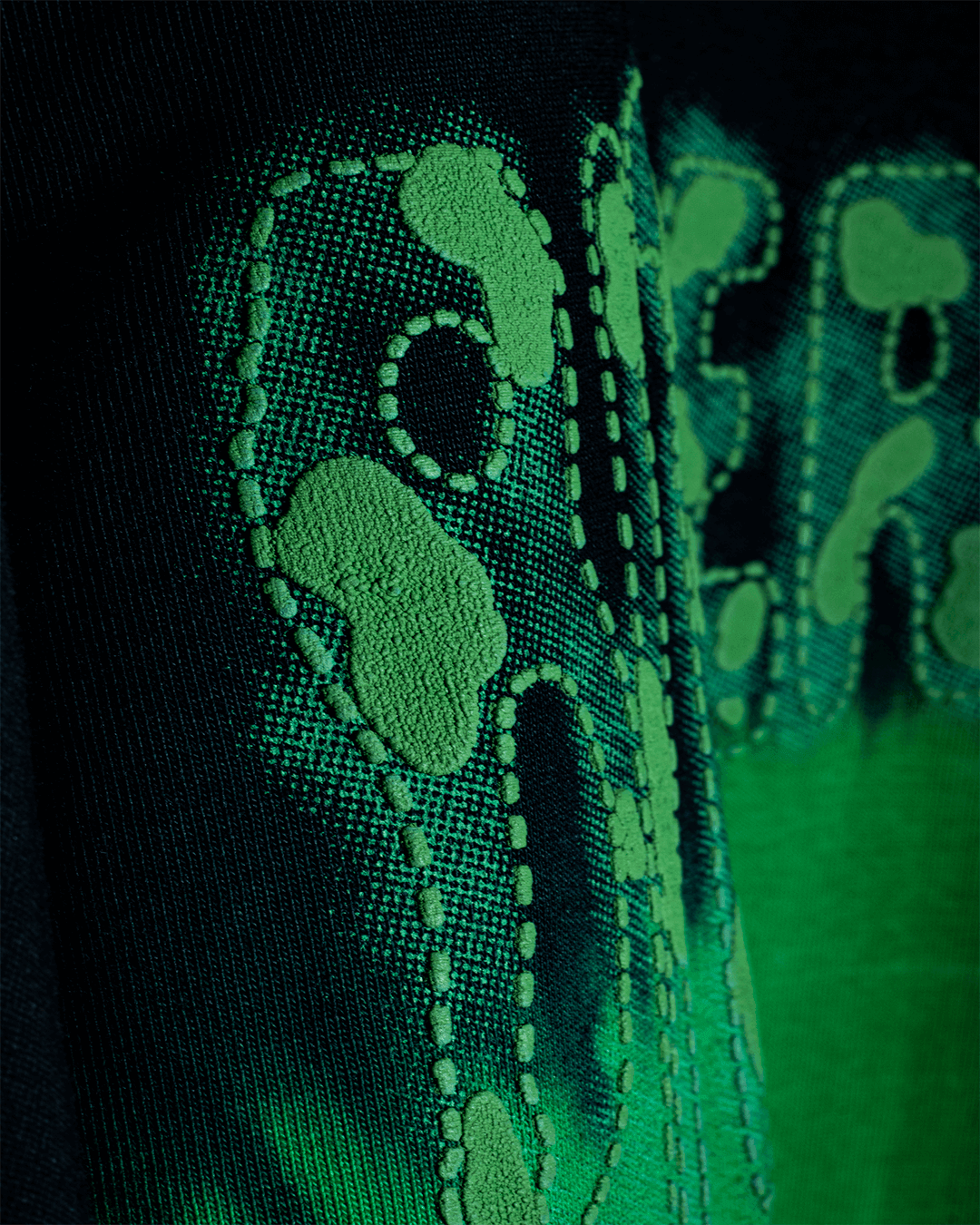 Close-up of green embroidered streetwear graphic design on black fabric