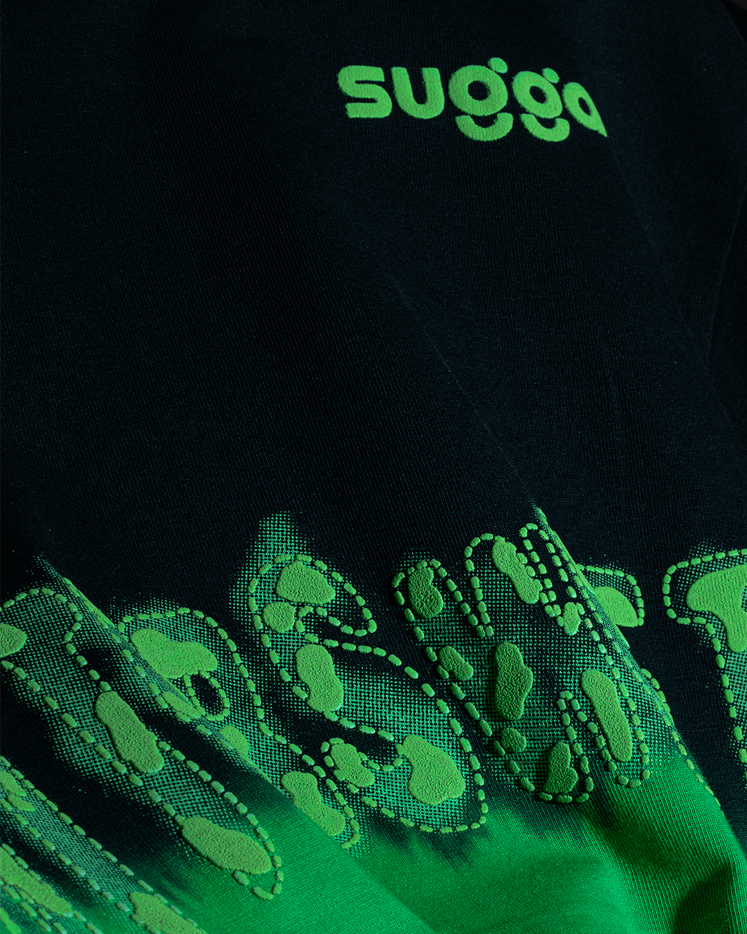 Close-up of black streetwear fabric with raised neon green graphic and 'sugga' text print