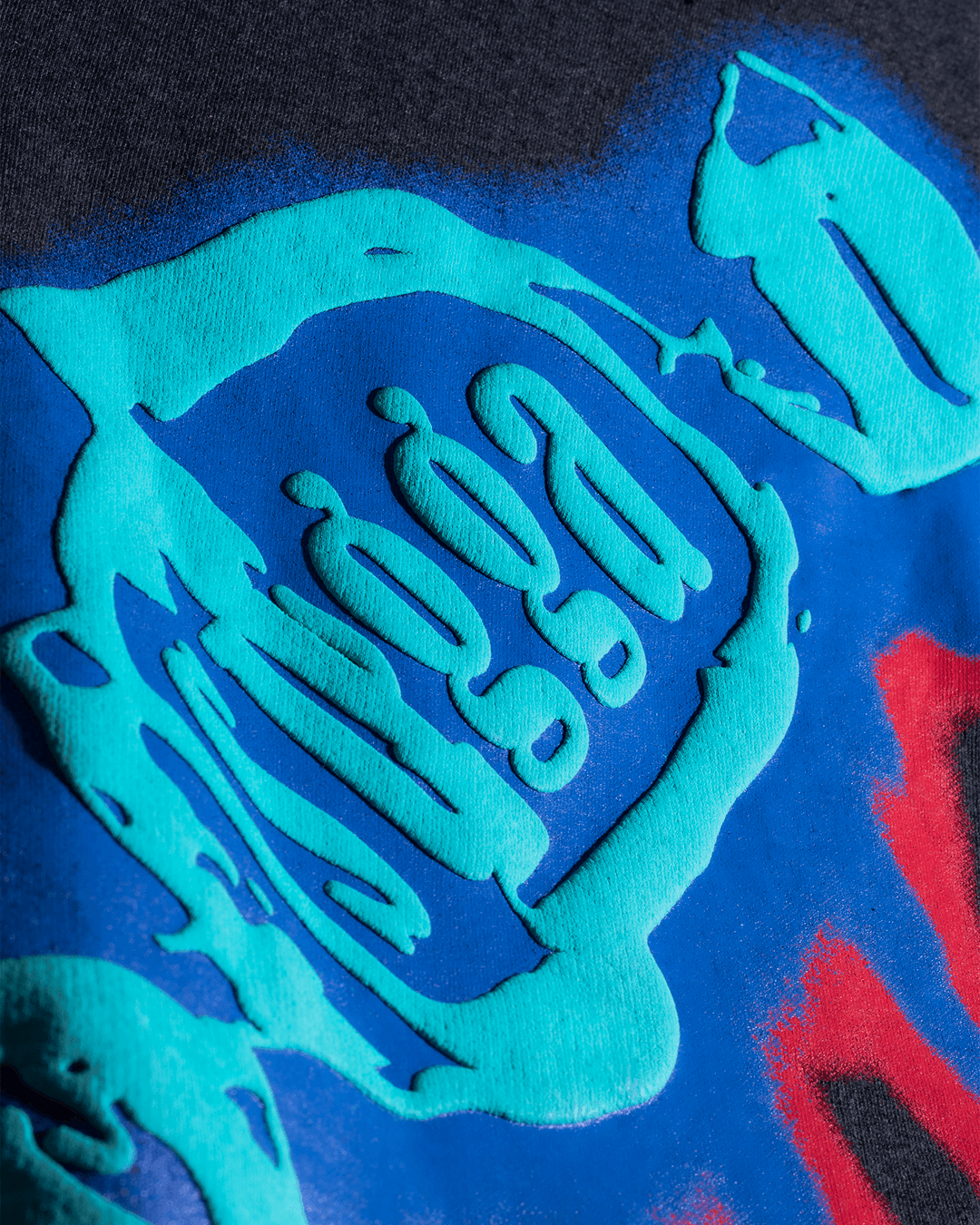 Close-up of streetwear graphic print with raised turquoise and blue abstract design on fabric