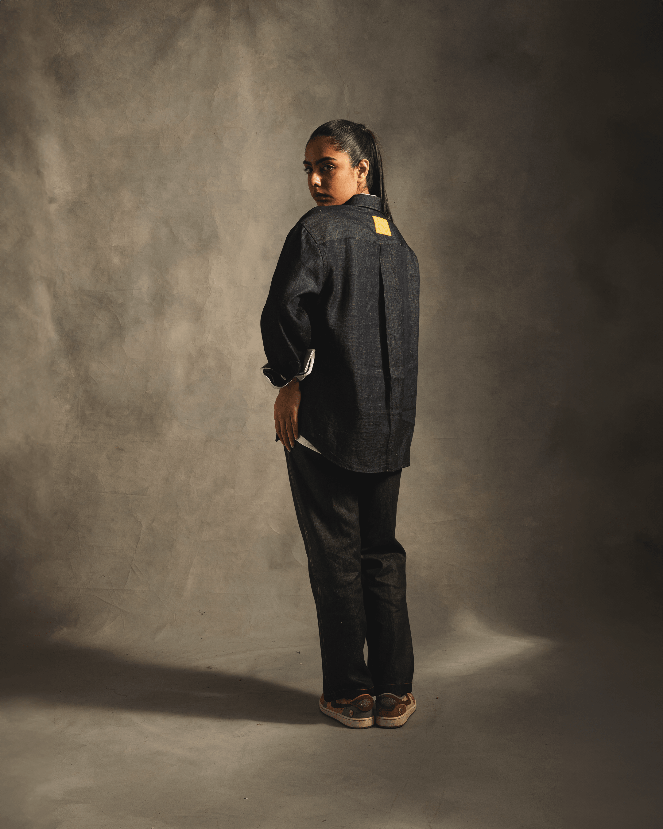 Model wearing relaxed fit blue denim shirt and matching pants in studio setting