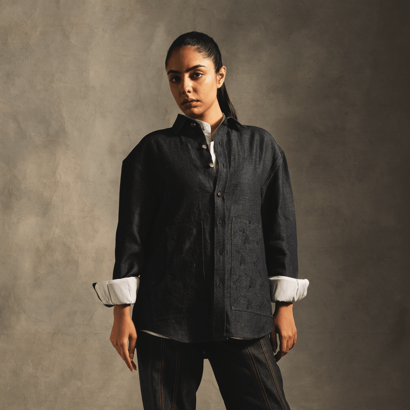 Woman wearing oversized blue denim shirt with front pockets and rolled sleeves, streetwear style