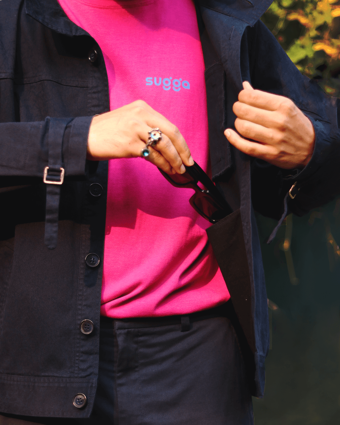 Streetwear style with black jacket, pink graphic t-shirt, and sunglasses in pocket