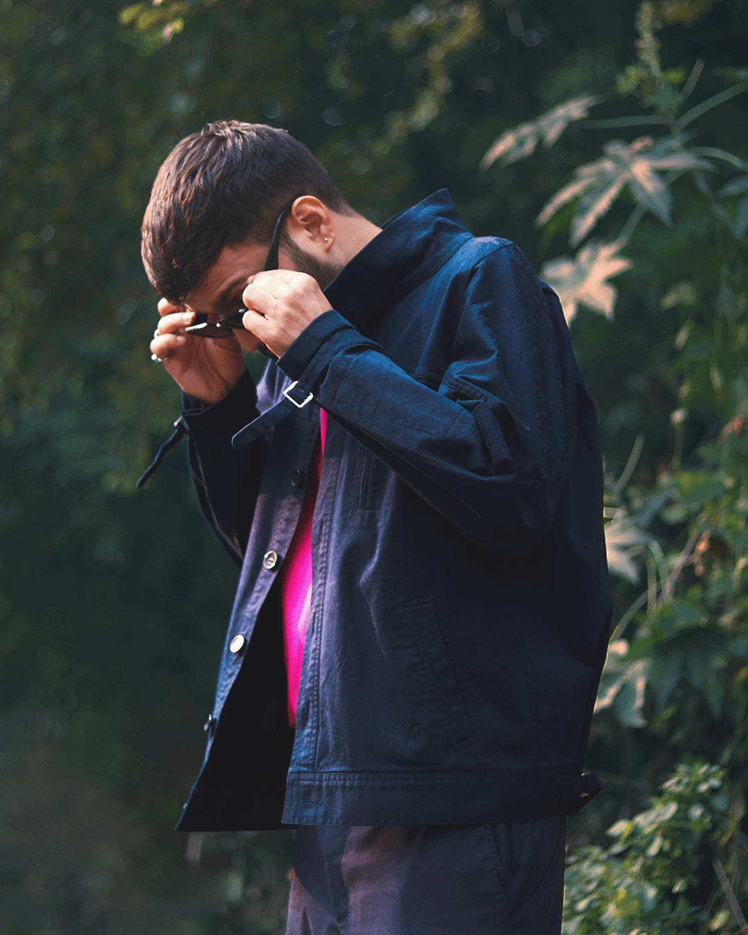 Man outdoors in stylish blue jacket, pink shirt, sunglasses, streetwear fashion