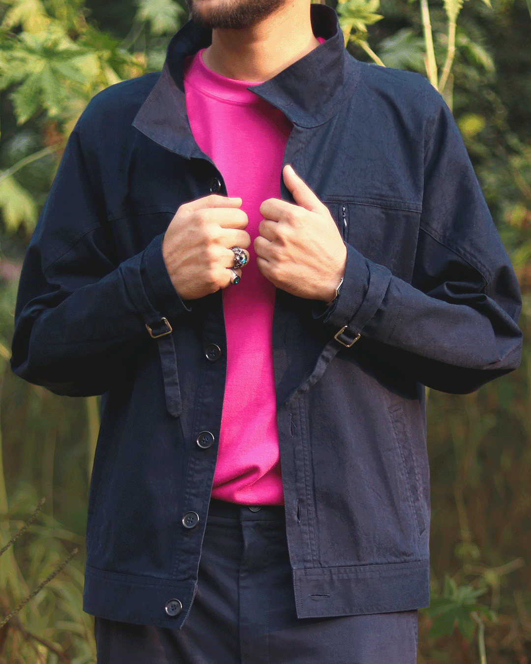 Man wearing a navy blue streetwear jacket over a bright pink shirt outdoors