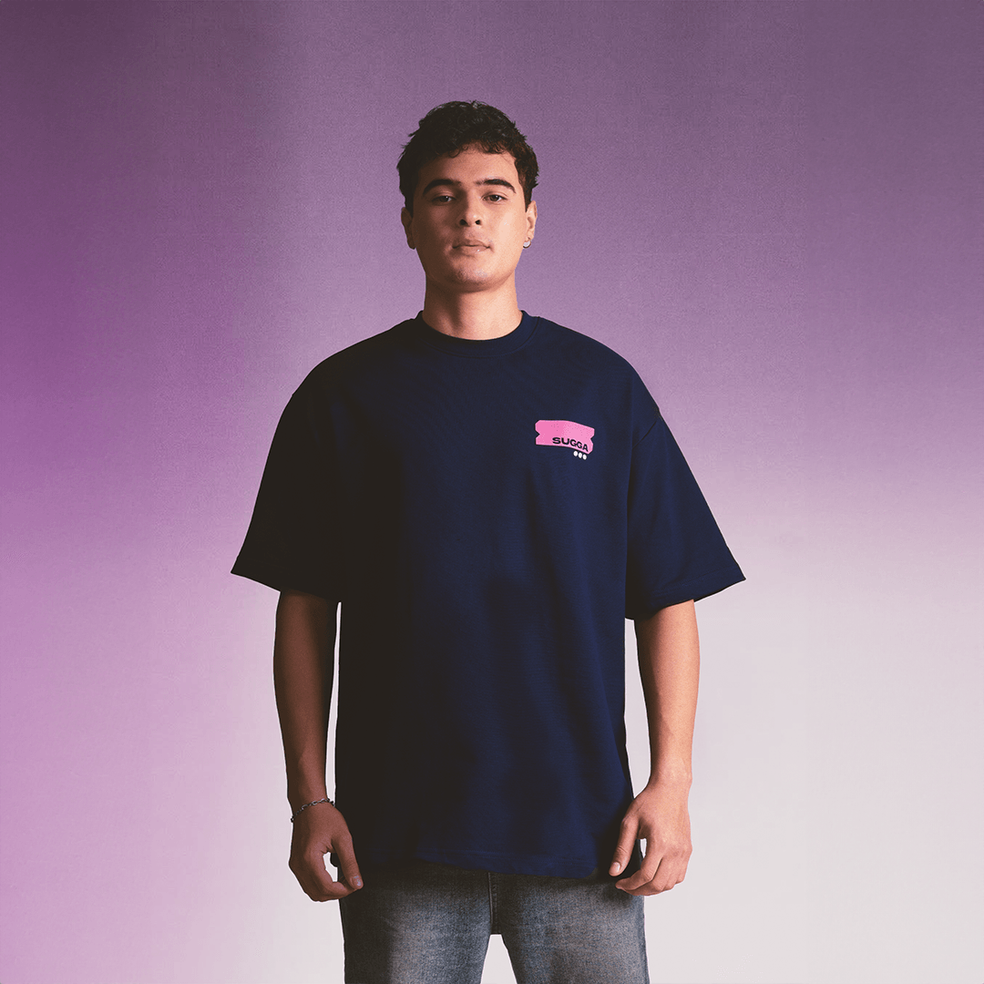 Man wearing navy oversized streetwear t-shirt with pink chest graphic, purple background