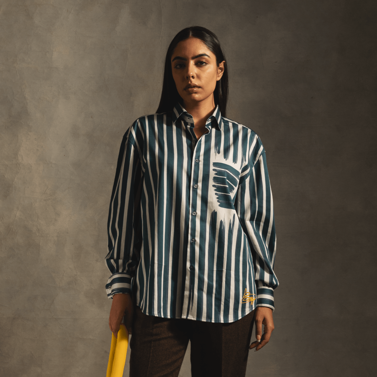 Woman modeling a blue and white striped streetwear shirt with abstract pocket detail