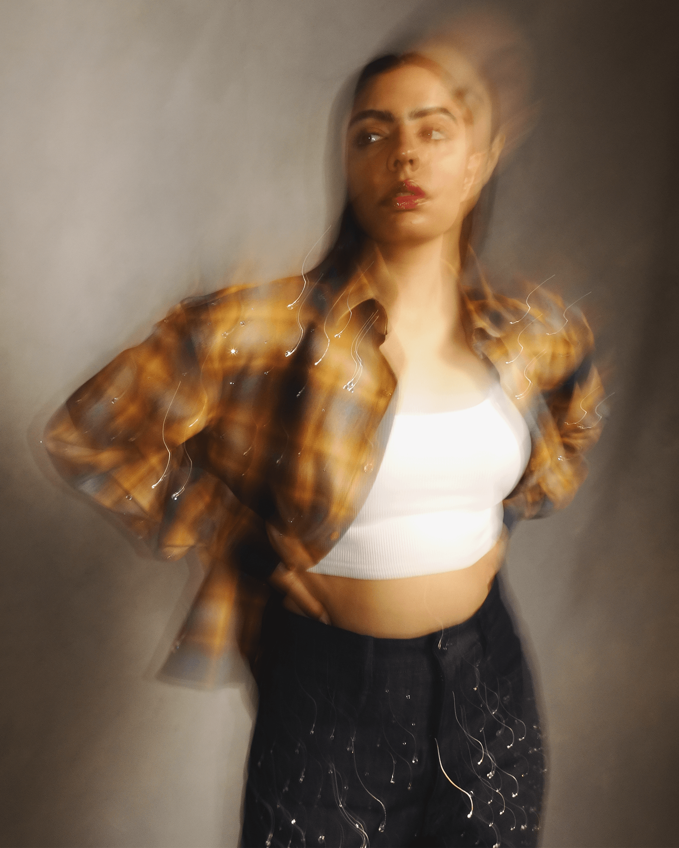 Woman in a trendy plaid shirt, white crop top, and black pants with artsy motion blur