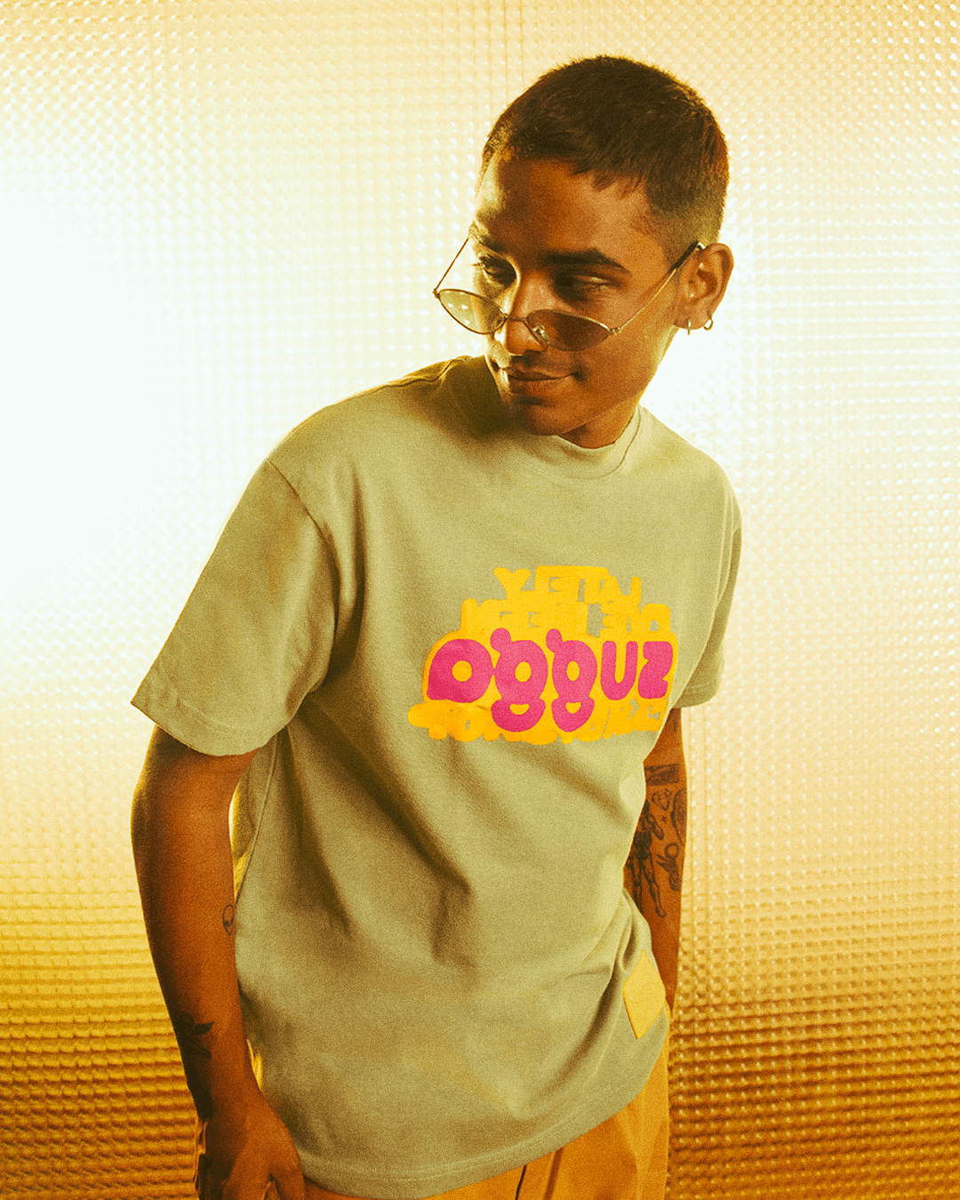 Man in streetwear t-shirt with colorful graphic print and sunglasses, yellow background