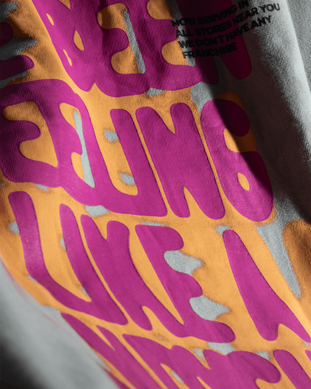 Close-up of streetwear graphic t-shirt with bold pink and orange lettering design