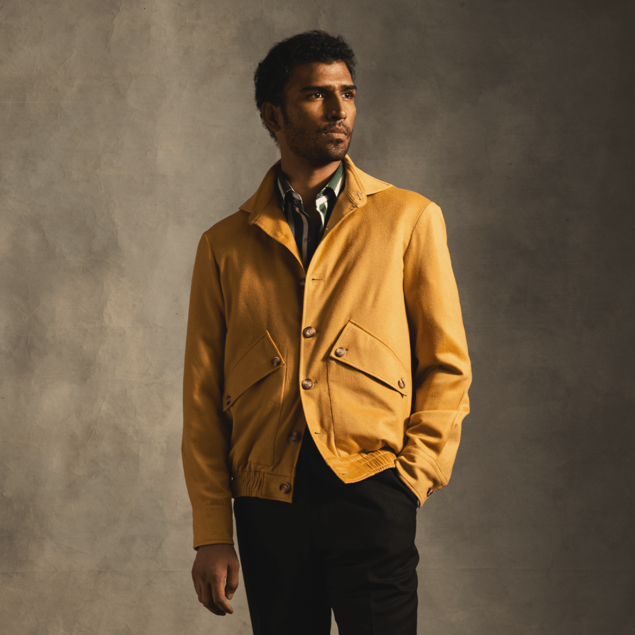 Man wearing a yellow cashmere bomber jacket and striped shirt, modern streetwear fashion