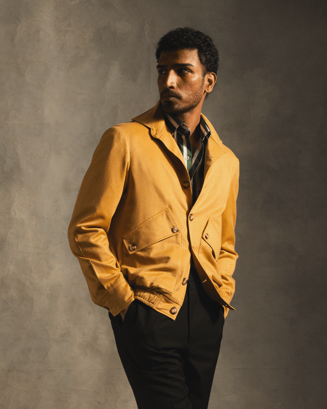 Man wearing a mustard yellow cashmere bomber jacket and striped shirt, stylish streetwear look