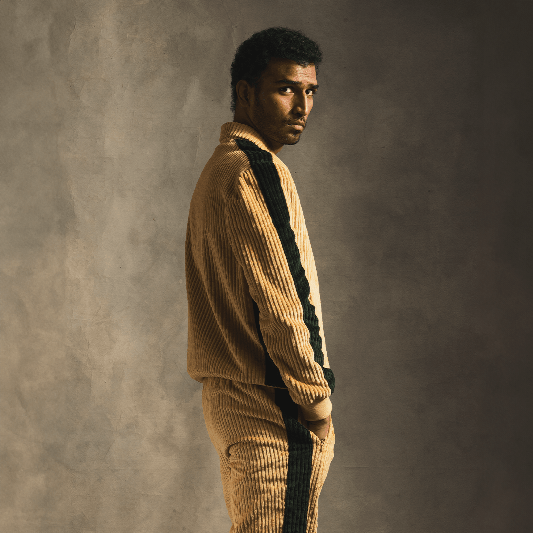 Cream corduroy track jacket with black stripes, streetwear style, worn by a male model.