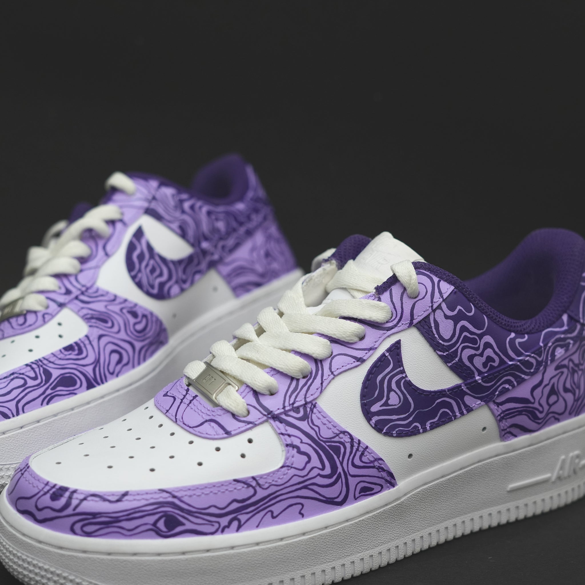 White and purple streetwear sneakers with abstract line pattern on black background