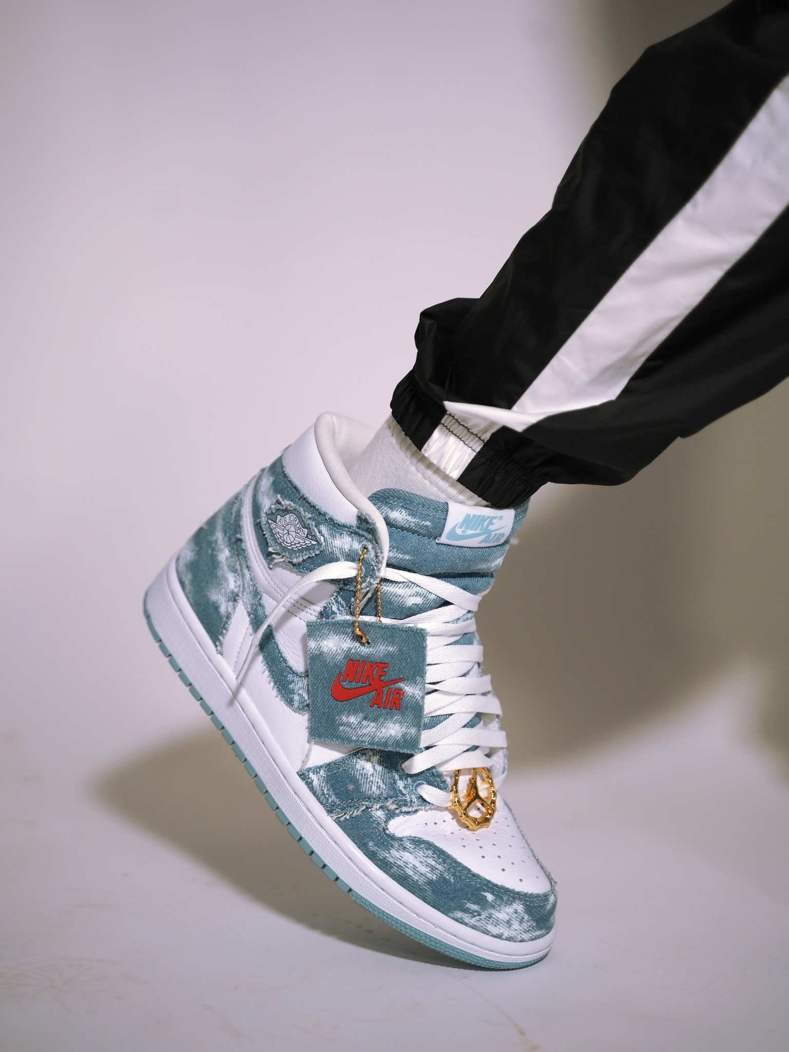 Close-up of Nike Air Jordan high-top sneaker in blue and white, worn with black track pants