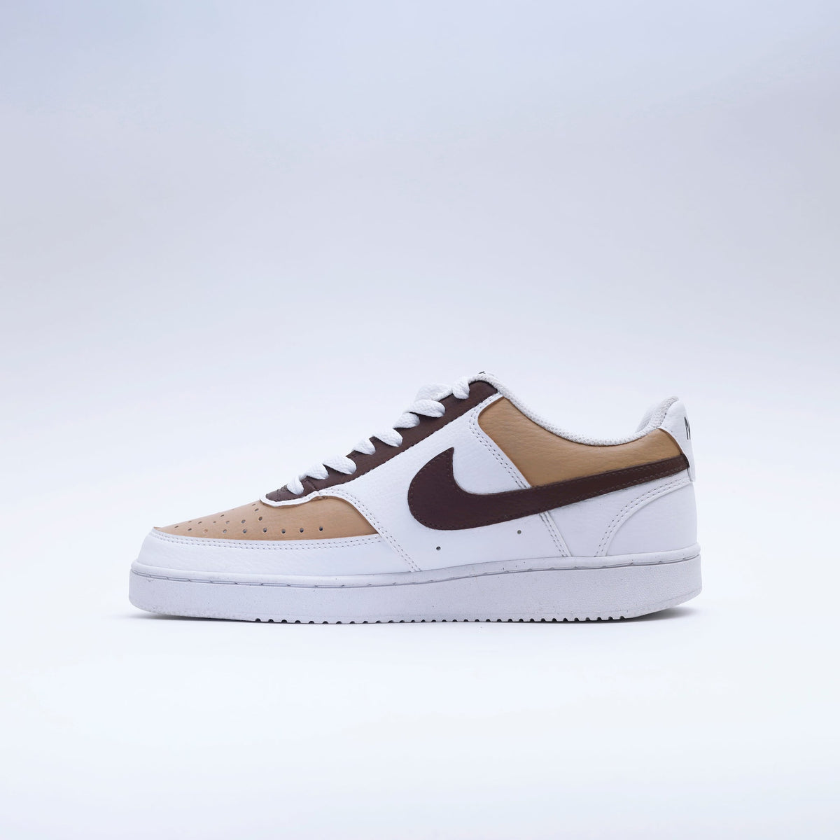 White and tan low-top sneaker with brown swoosh, modern streetwear shoe on clean background