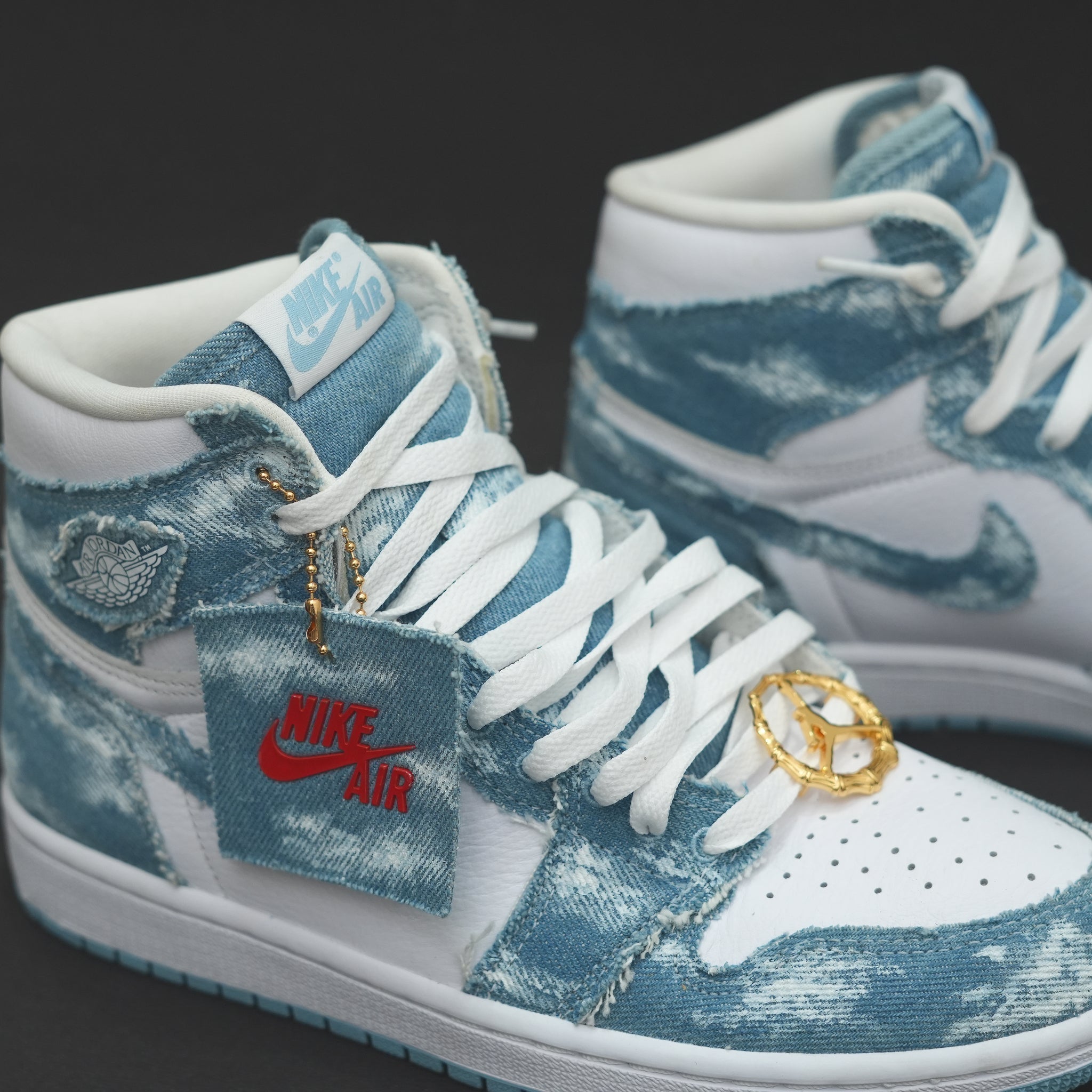 Close-up of Nike Air Jordan high-top sneakers with blue denim accents and gold charms