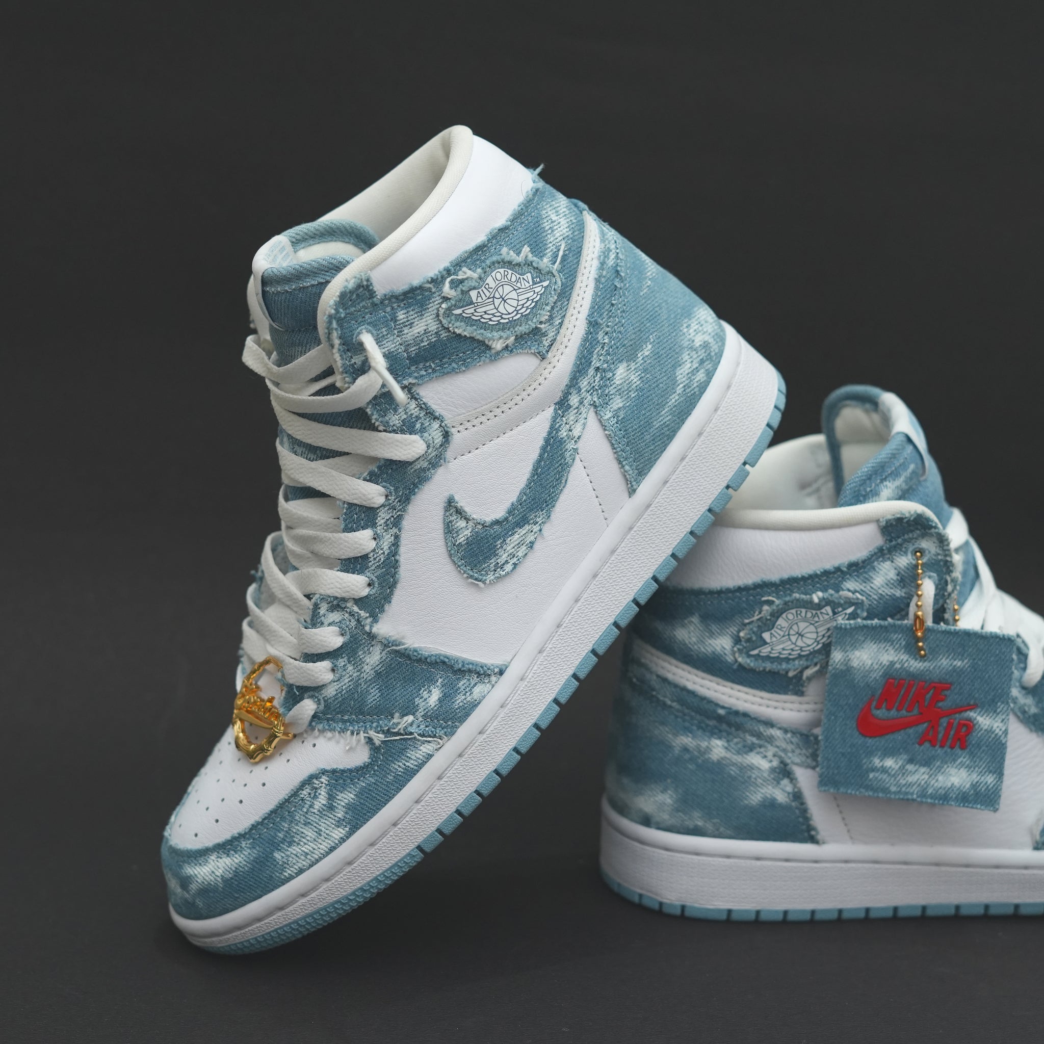 White and blue denim high-top sneakers with Nike Air and Air Jordan logo, on black background.