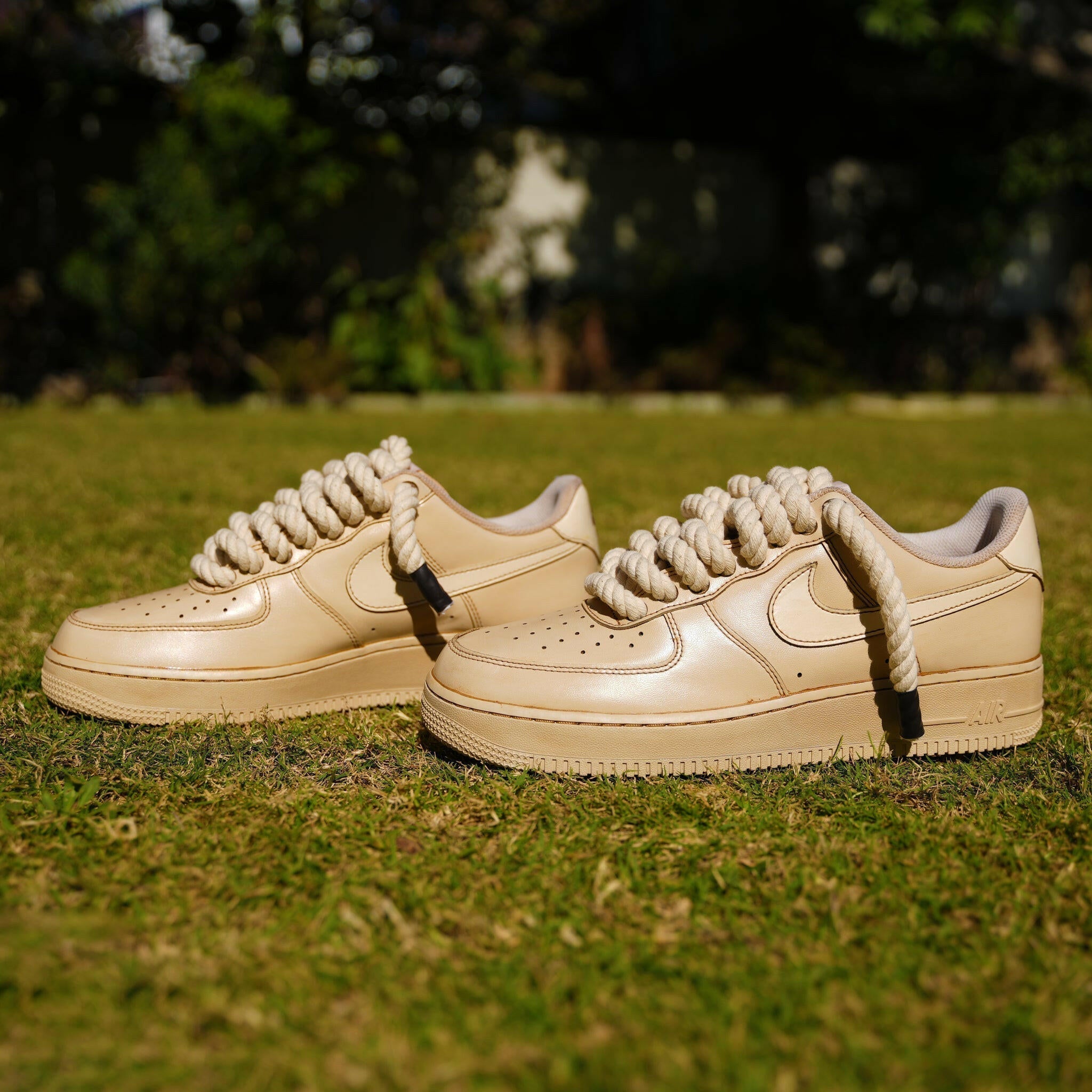 Beige leather sneakers with chunky rope laces on grass, streetwear style footwear
