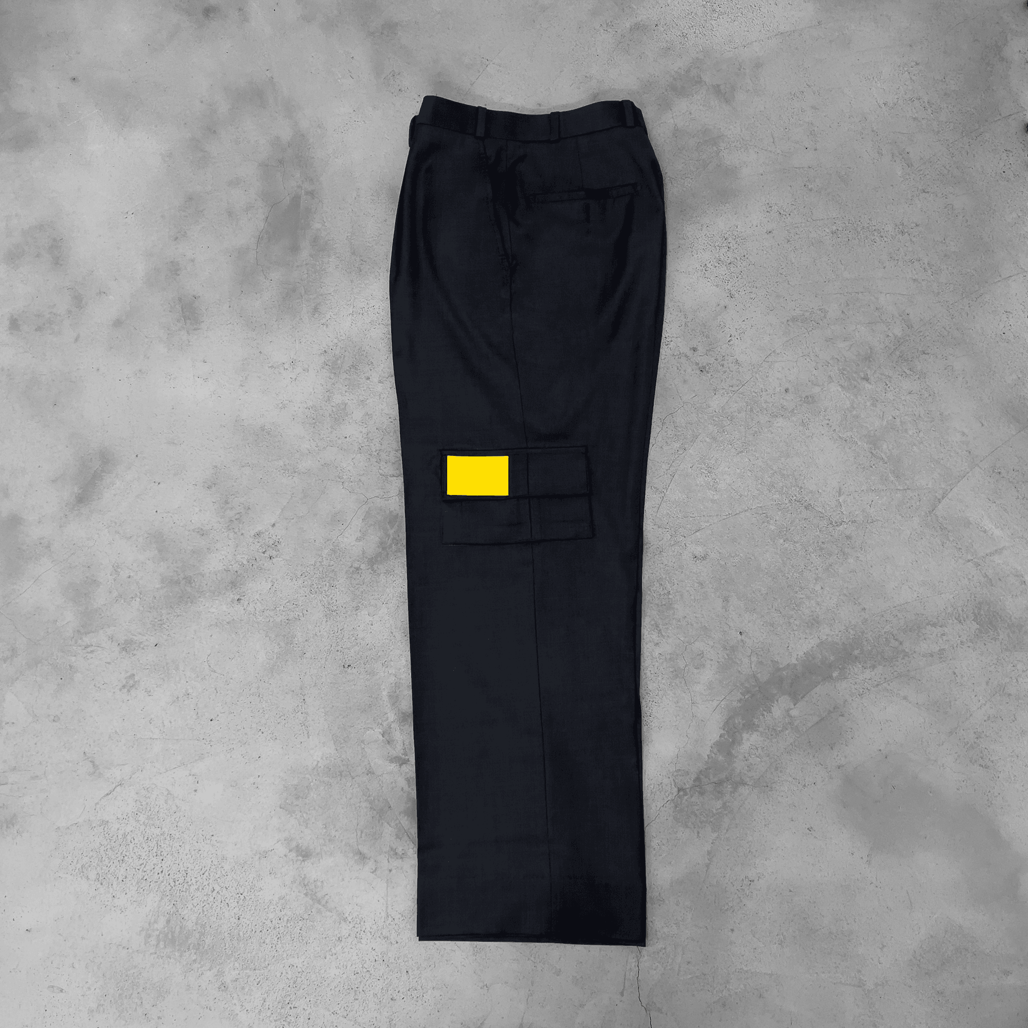 Dark grey streetwear cargo pants with yellow patch pocket on concrete background