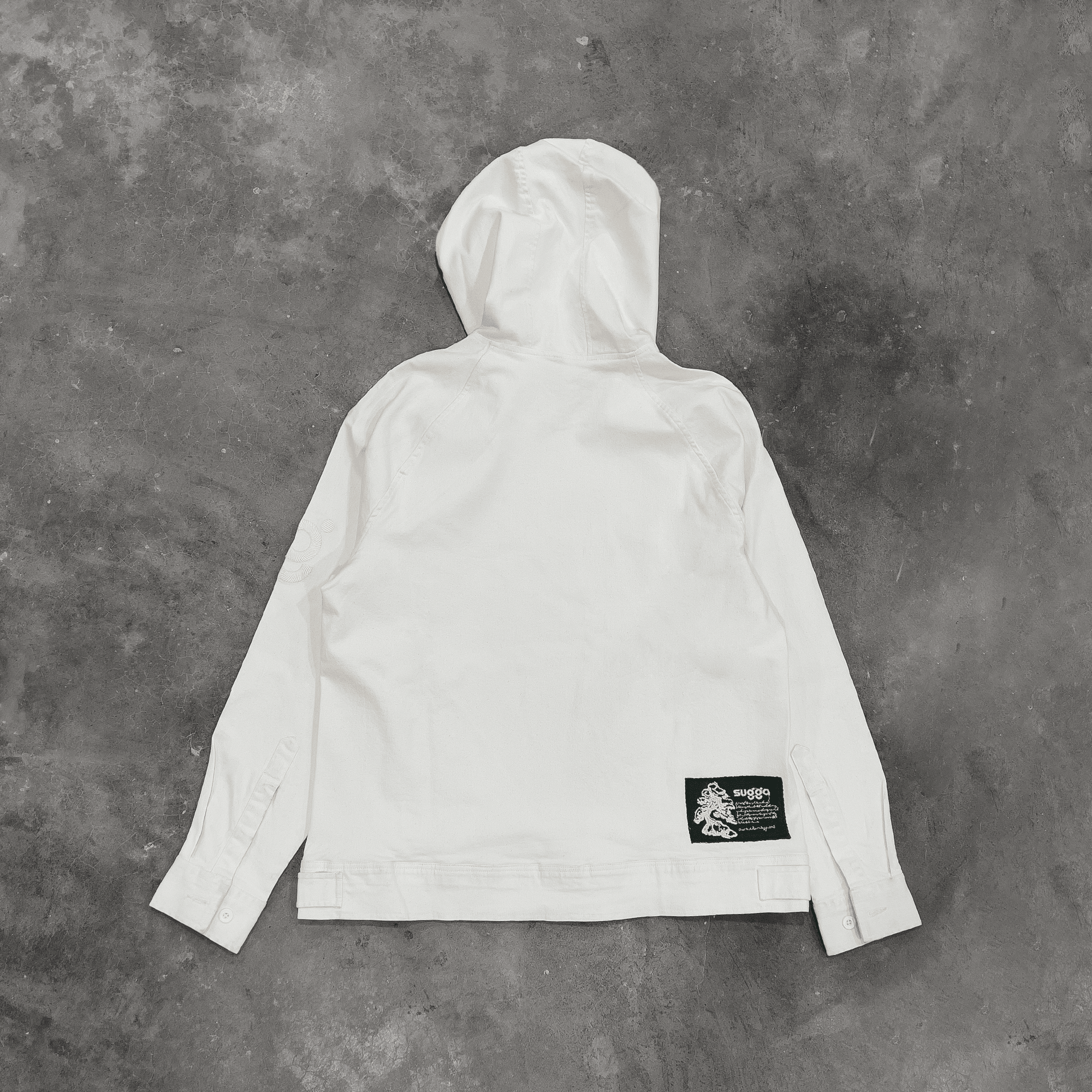 White denim streetwear hooded jacket flat lay with black graphic patch on back
