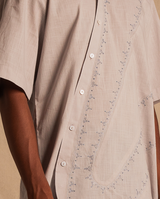 Beige short sleeve shirt with delicate blue embroidery and white buttons, streetwear style.