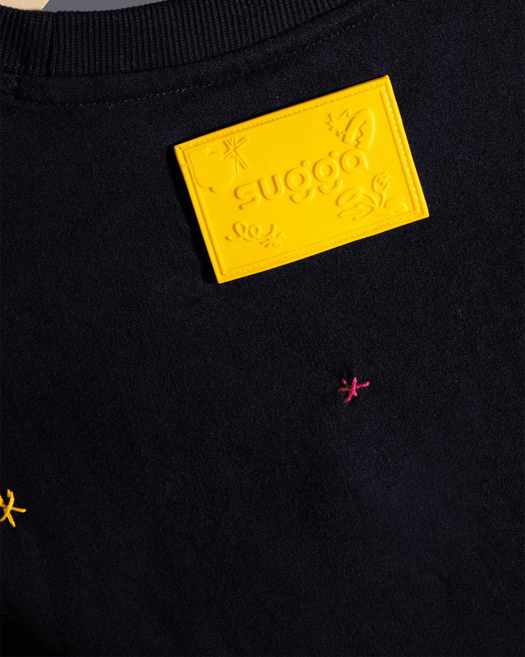 Close-up of black streetwear shirt with yellow embossed patch and colorful embroidered details