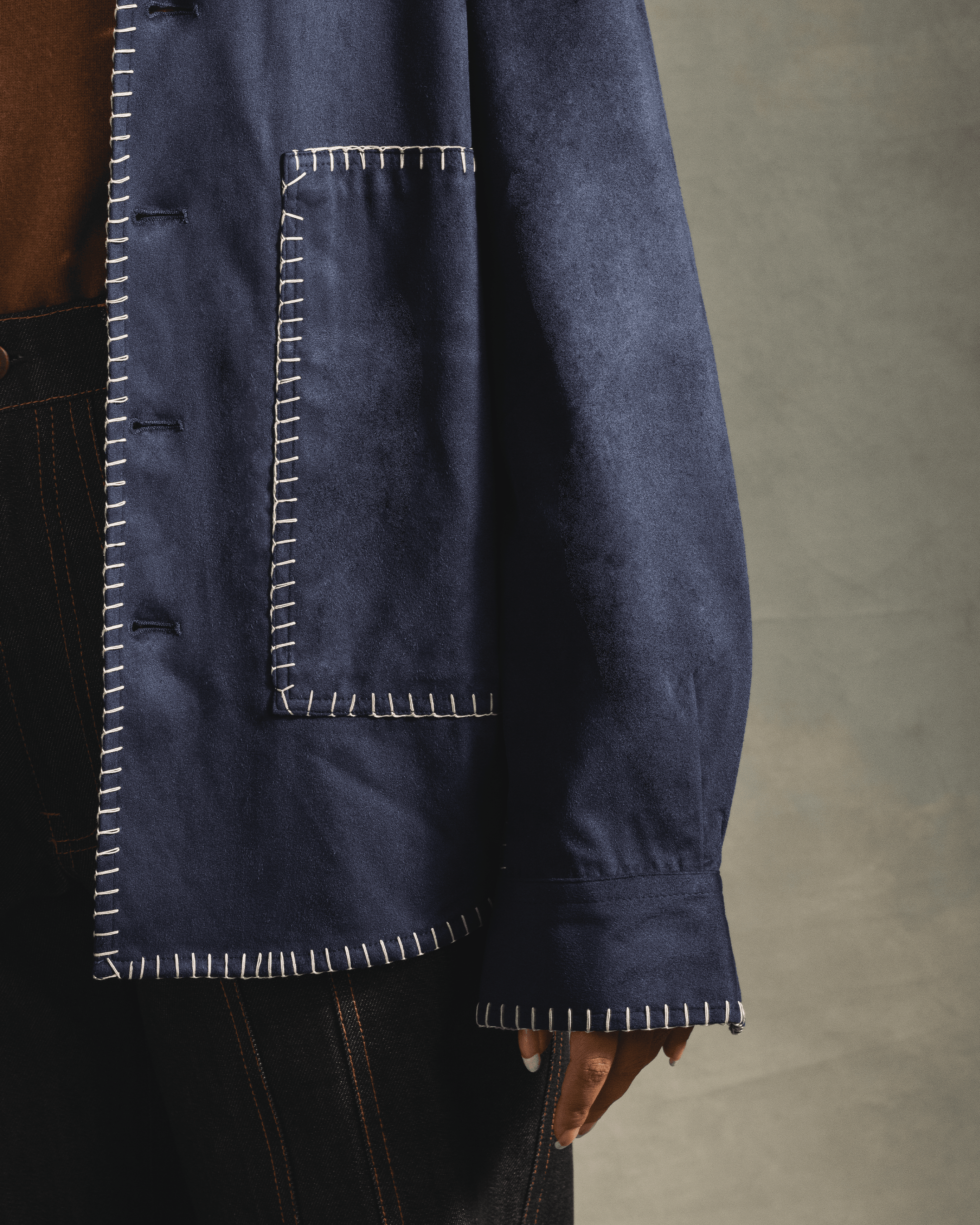 Close-up of navy blue streetwear jacket with white contrast stitching and large front pocket
