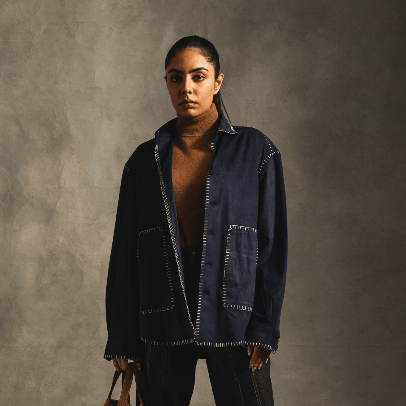 Woman wearing dark oversized streetwear jacket with contrast stitching and brown turtleneck
