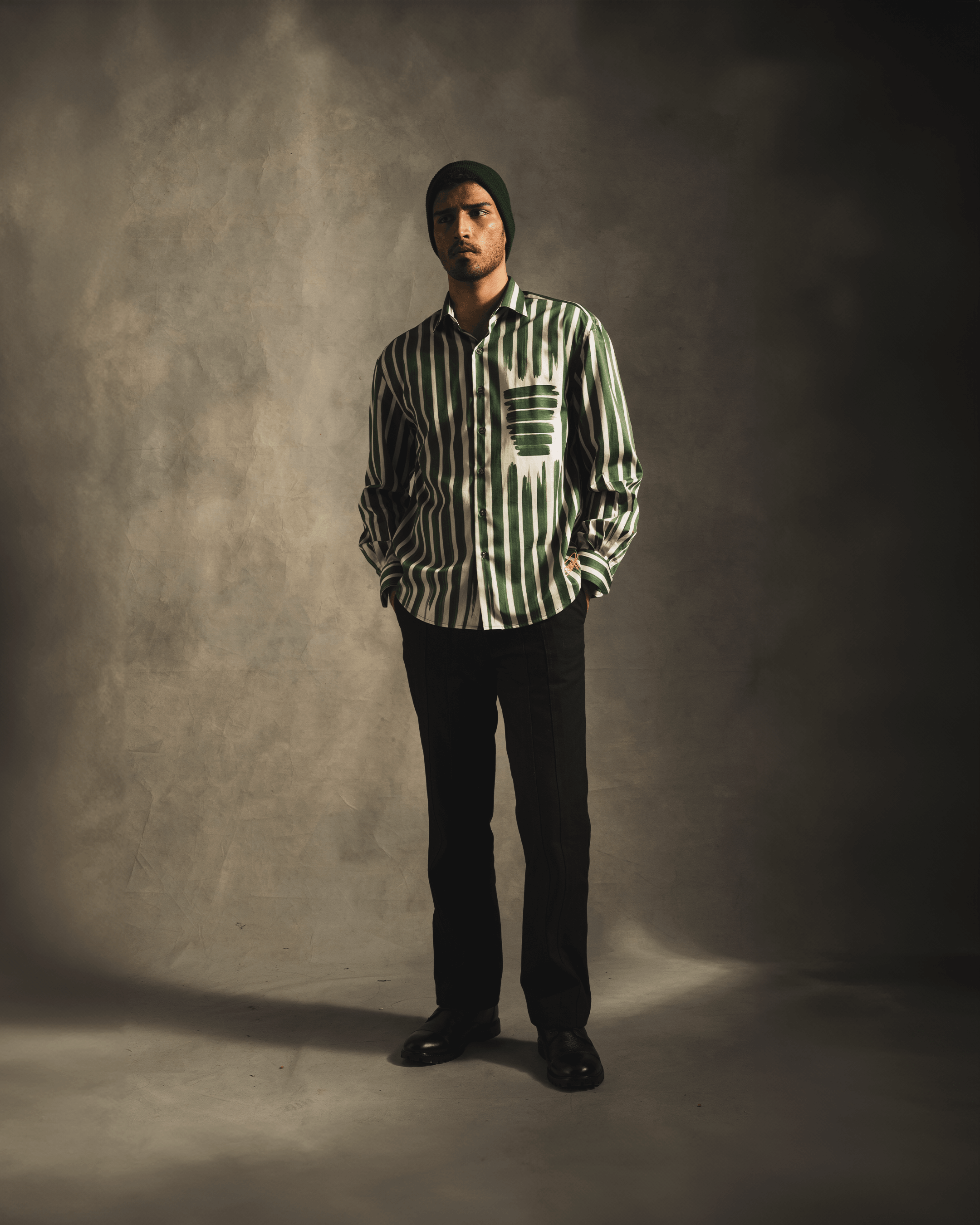 Man modeling green and white striped streetwear shirt, black pants, and black beanie