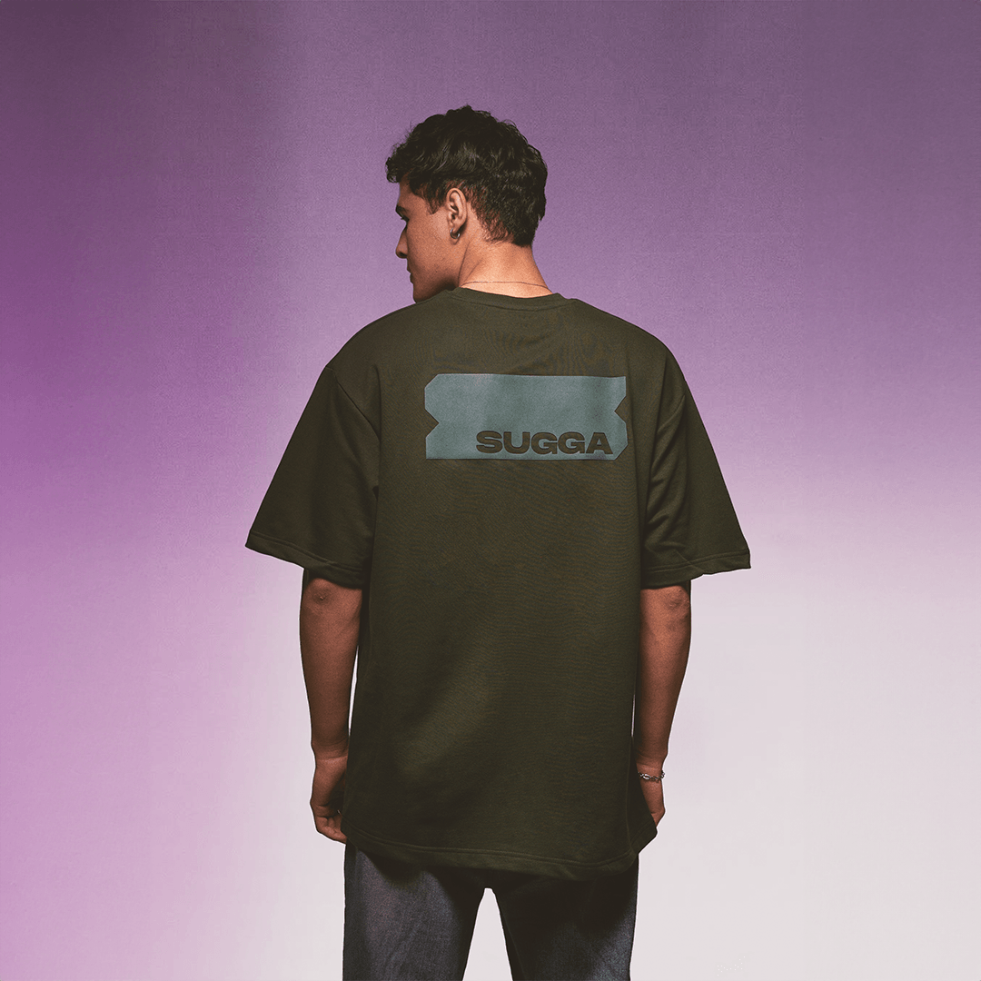 Back view of person wearing black SUGGA streetwear t-shirt, purple gradient background