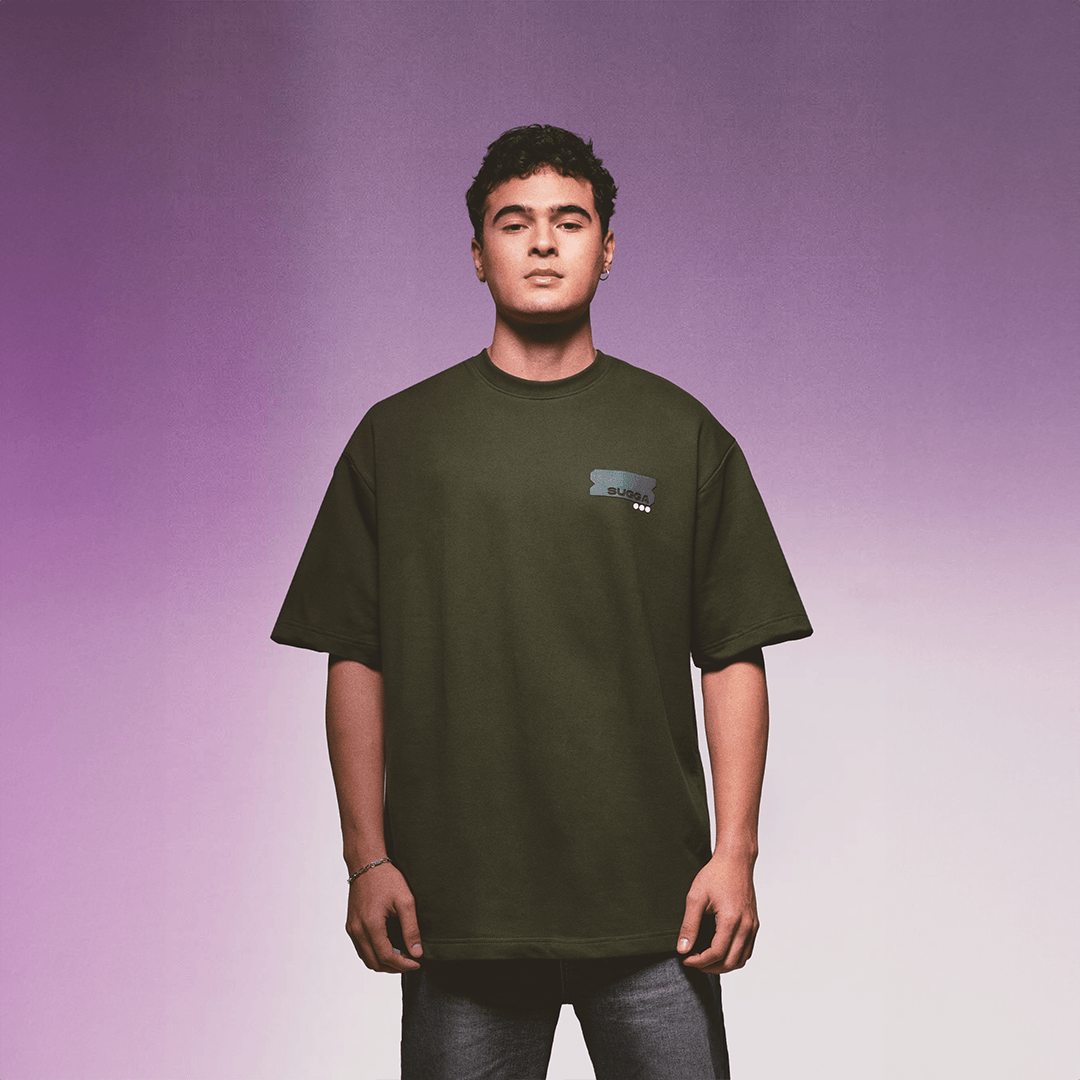 Man wearing oversized dark green streetwear t-shirt with graphic chest print, purple background
