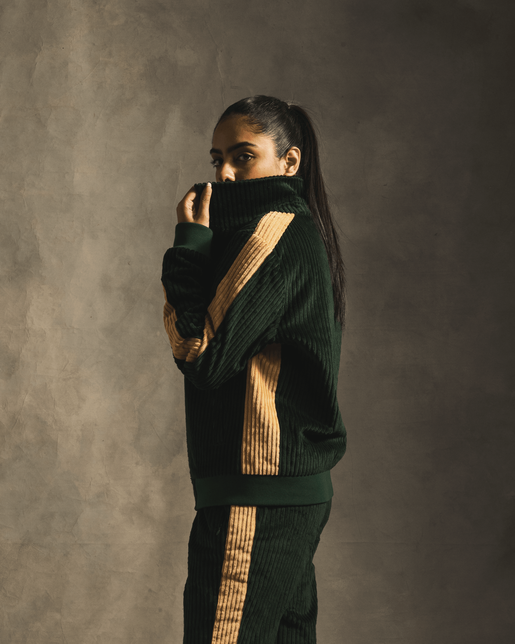 Woman in green corduroy track jacket and pants with tan stripes, streetwear fashion