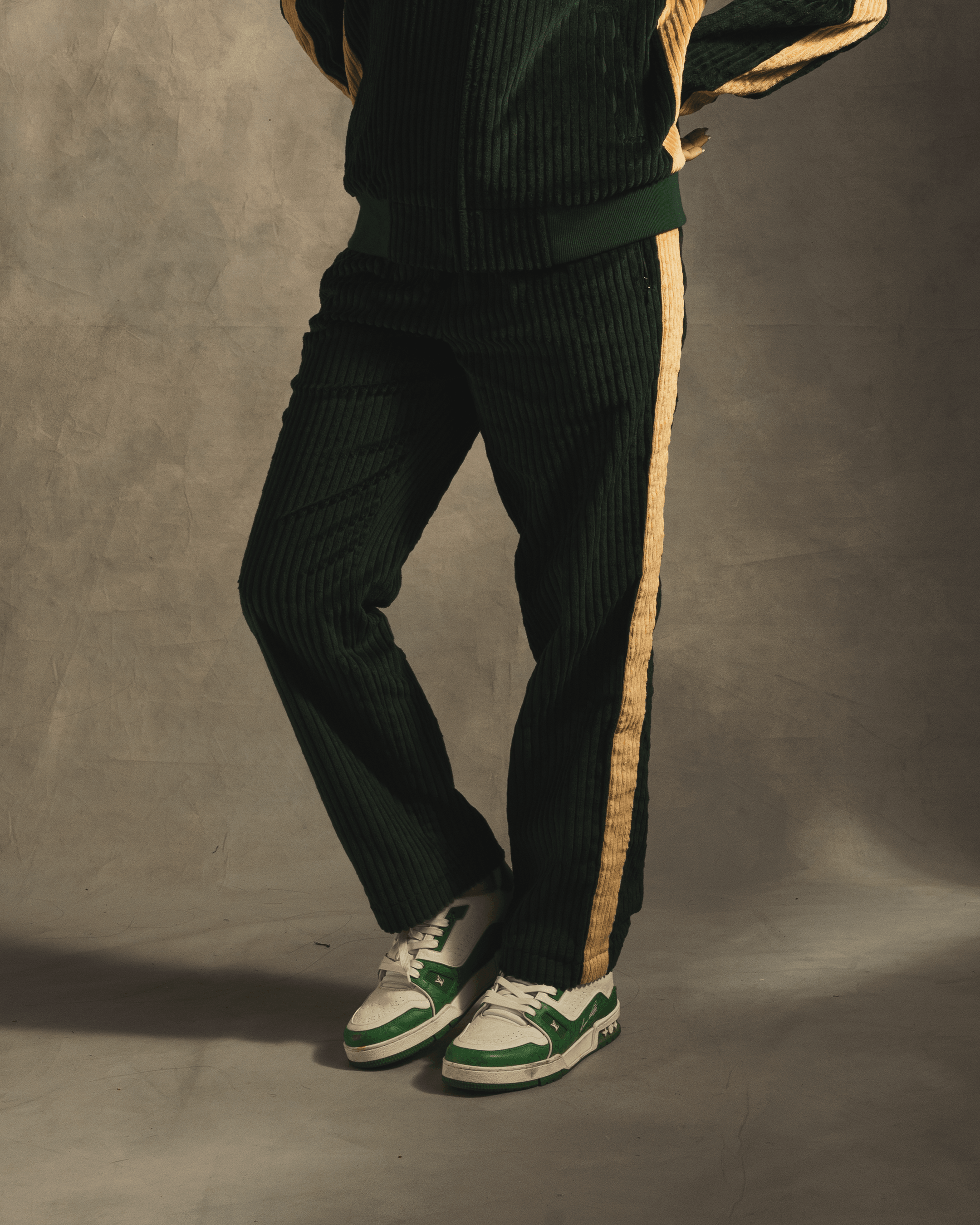 Green corduroy track pants with yellow side stripe, styled with white and green sneakers